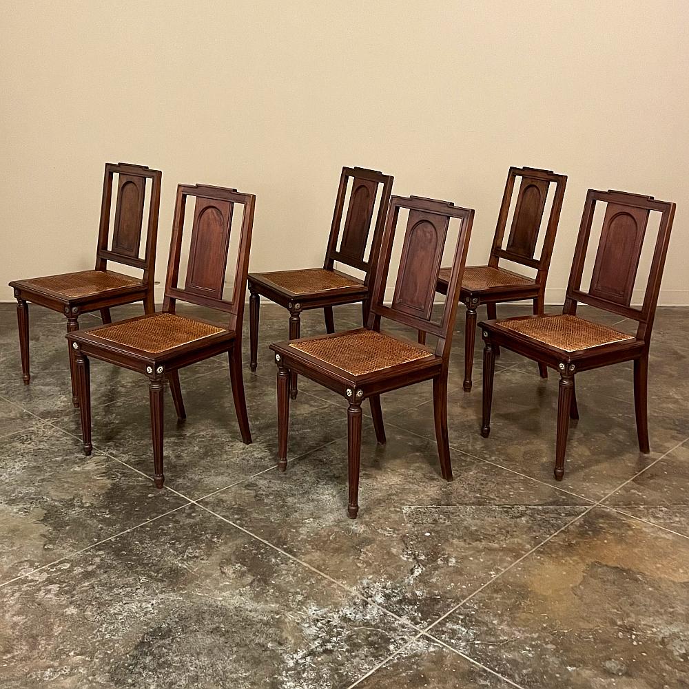 Set of 6 French walnut neoclassical dining chairs with cane seats are a marvel of understated elegance! The slat-backed seats feature a tailored, restrained architecture, while the seat apron and legs follow a timeless Louis XVI design complete with