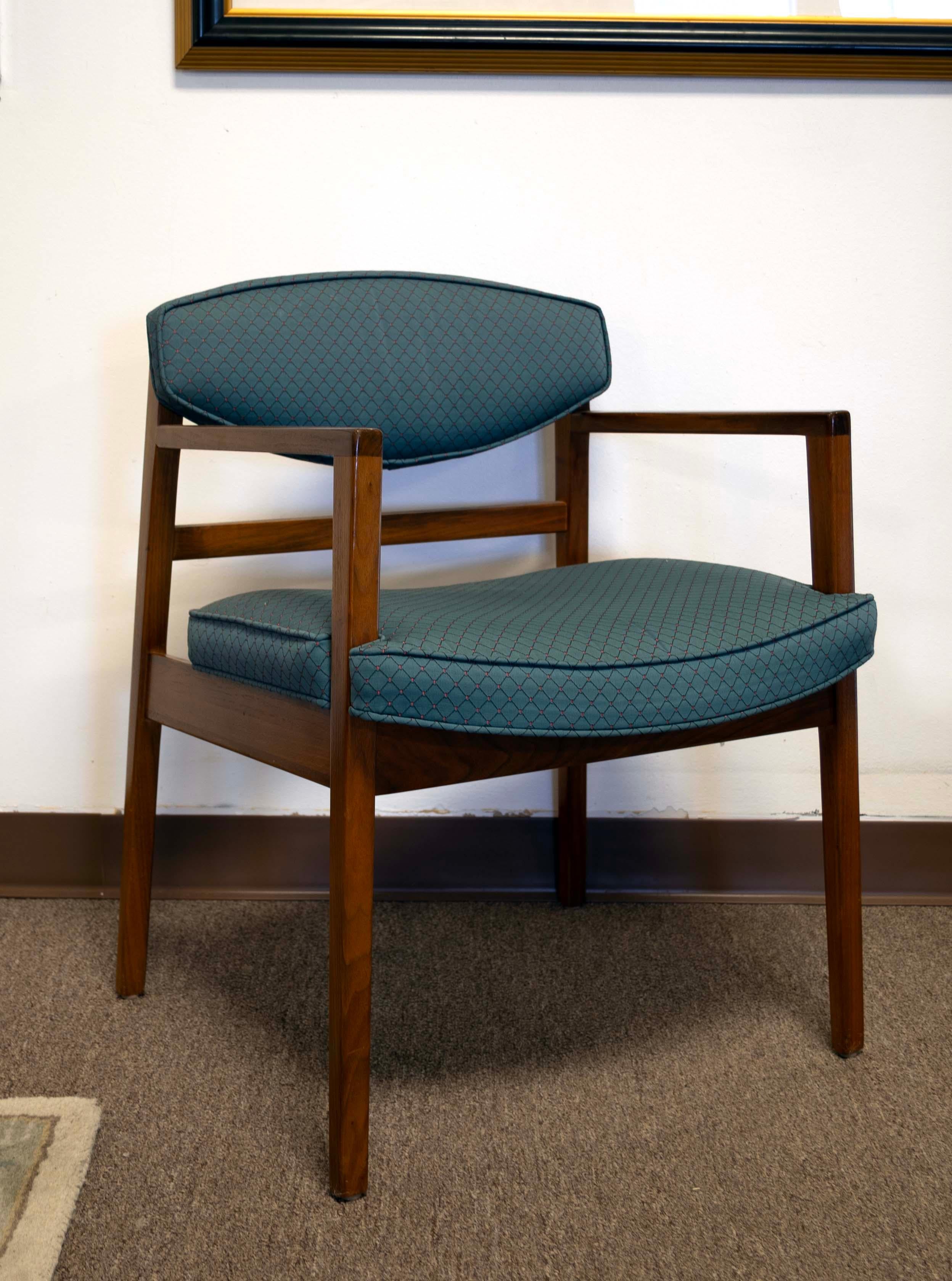 Elegant and sophisticated, this set of six George Nelson for Herman Miller chairs features two captain and four side chairs, all epitomizing classic Mid-Century Modern design. The warm walnut frames are beautifully complemented by the textured teal