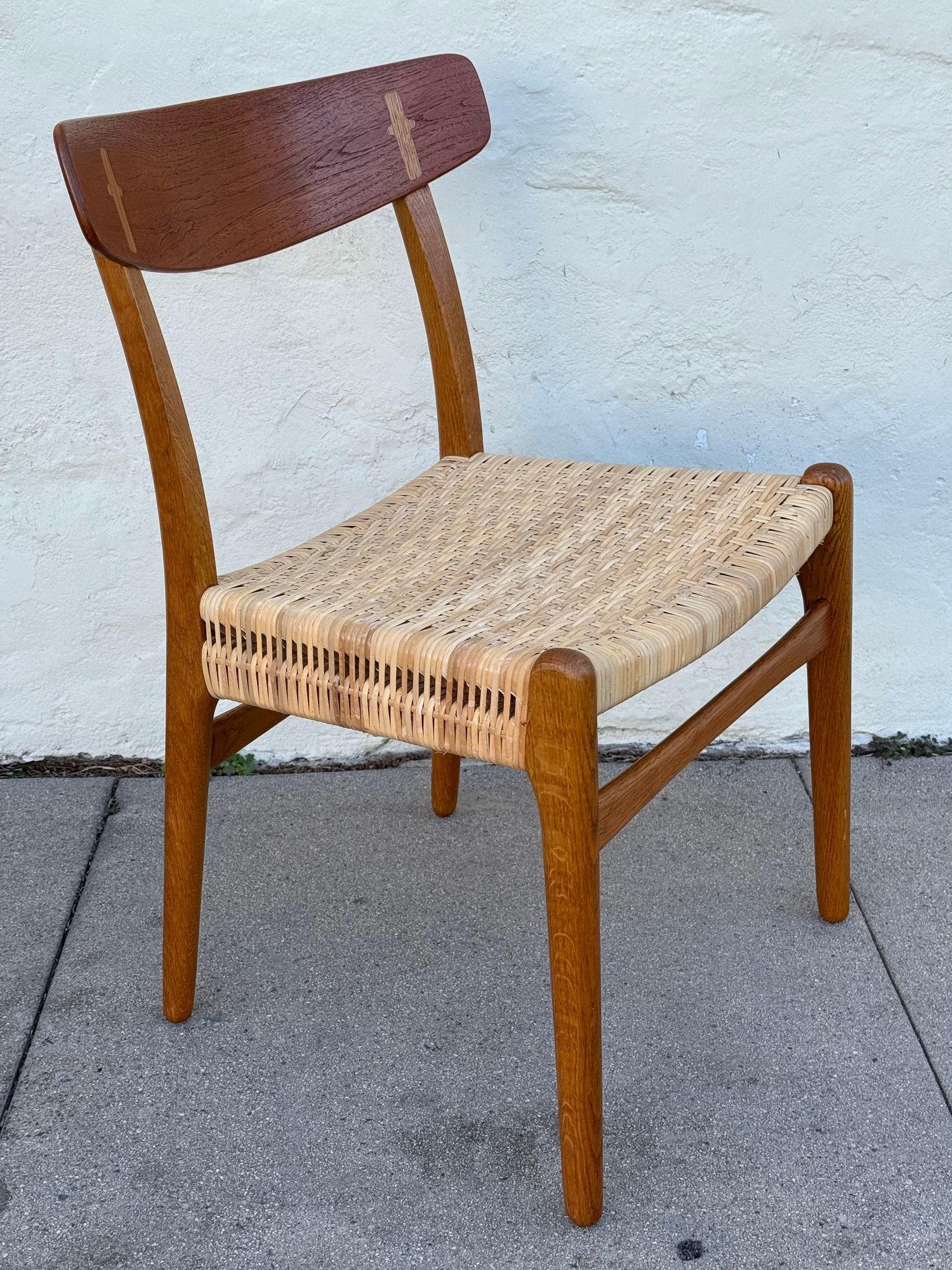 Set di sei sedie da pranzo Hansen CH 23, disegnate nel 1951 e prodotte da Carl Hansen & Son. Le sedie sono state completamente restaurate. Schienale in teak con gambe in Oak. Sedile a bastone. Firmato con timbro impresso a fuoco sulla guida laterale