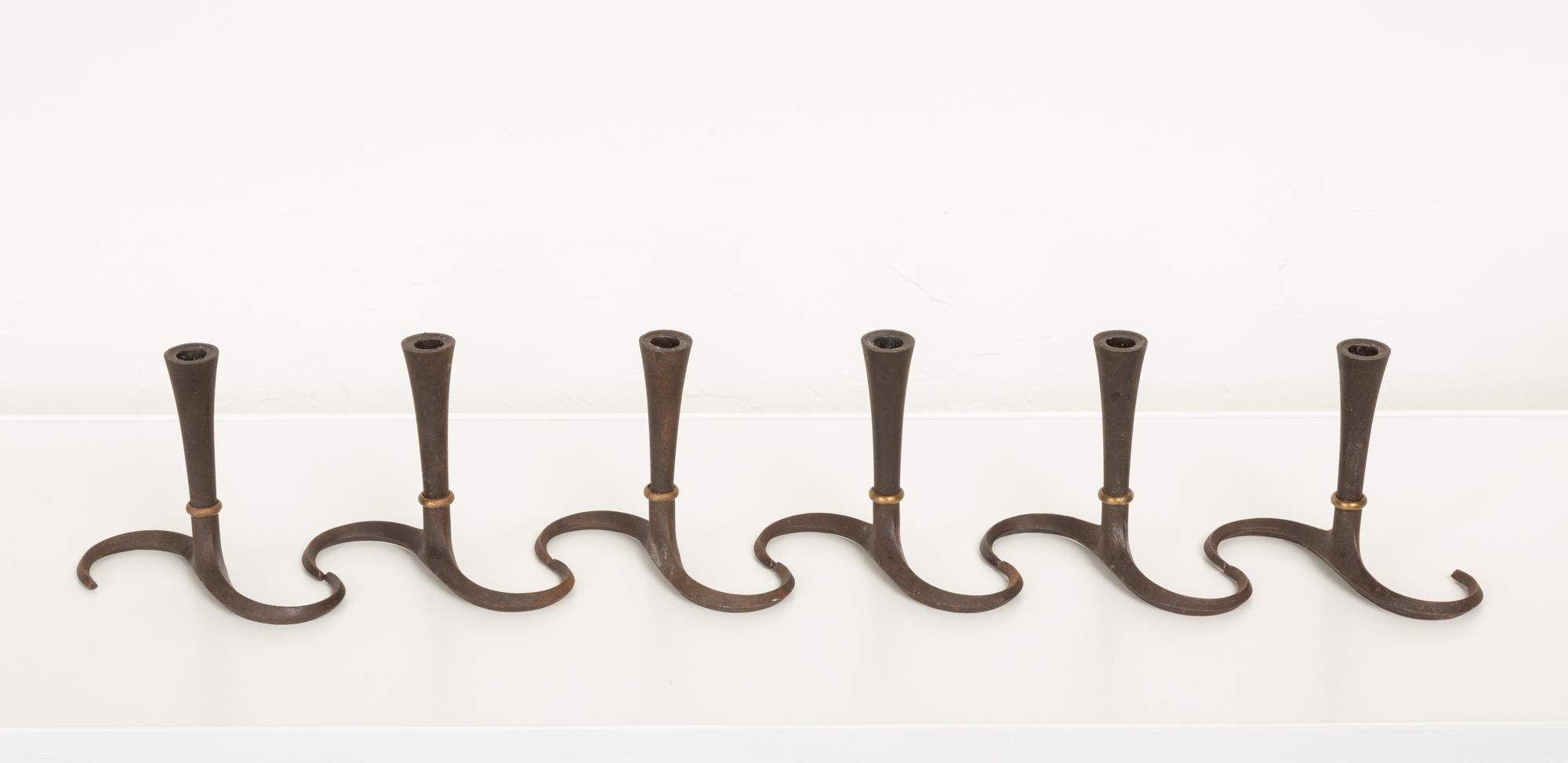 A set of six “S” candlesticks by Jens Quistgaard for Dansk. This rare example was produced in Denmark in the 1960s. They feature a cast iron body and curved base, with a patinated brass ring around the stem. Impressed [J.H.Q. Denmark] on