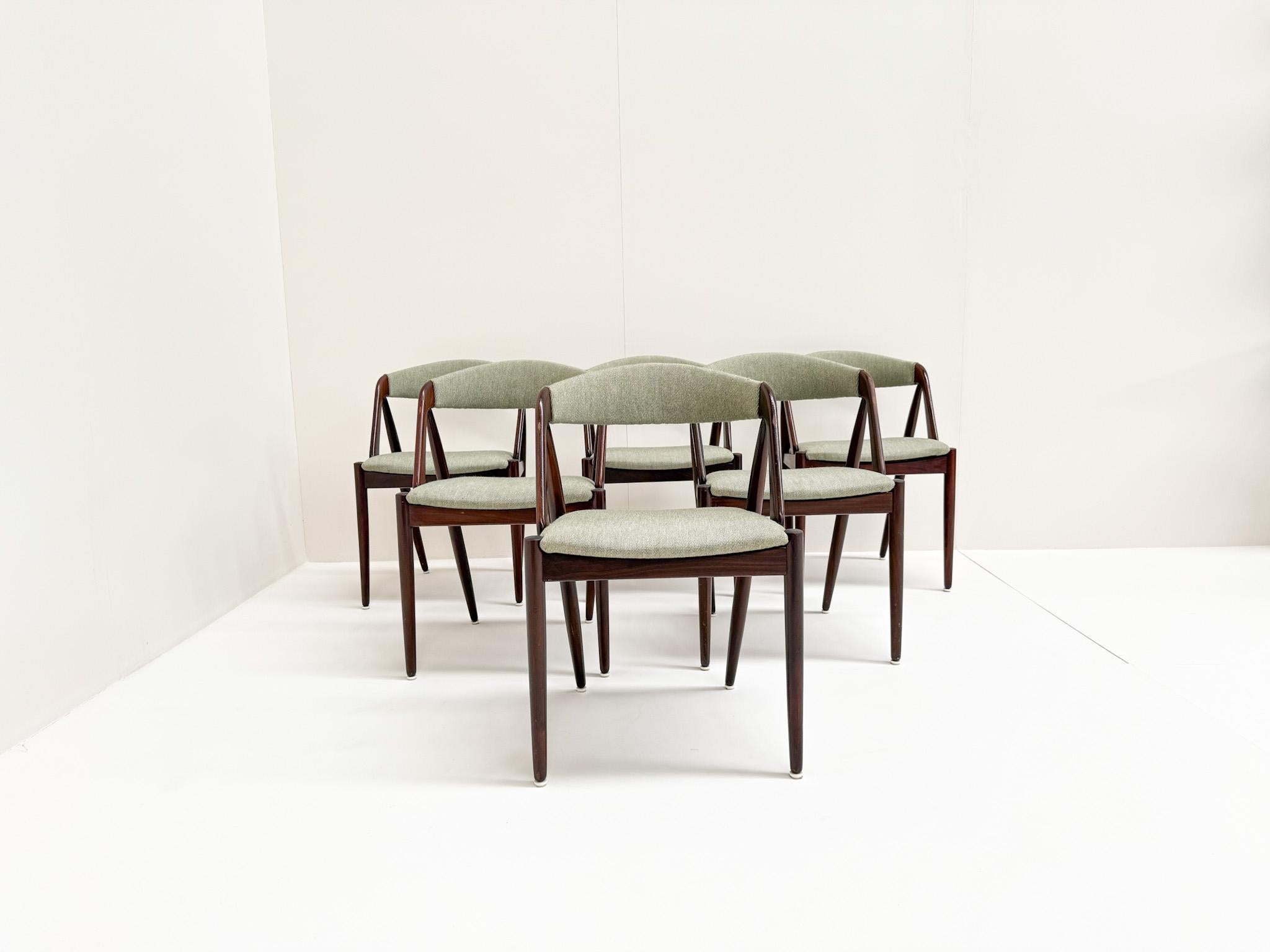 A rare and elegant set of six original Model 31 dining chairs designed by Kai Kristiansen in the 1960s. Crafted from rich solid teak wood with stunning sculptural lines and signature angled arms, these chairs are an iconic example of Danish