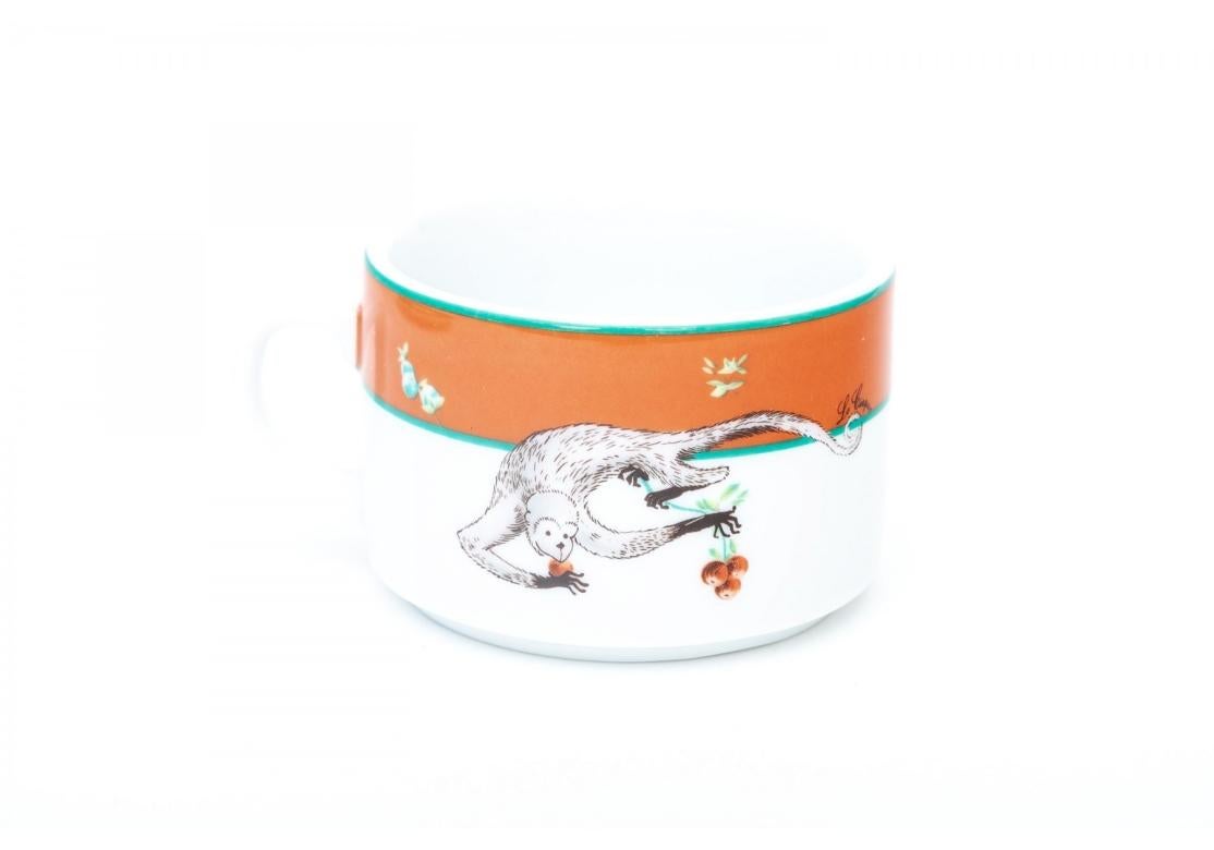 Set of six Limoges for Le Cirque assembled porcelain tea cups with orange band, green trim with imagery of monkeys picking fruit. The paired saucers with wide green band, fruit and orange trim. The saucers by Bernadaud, Limoges, France and the cups