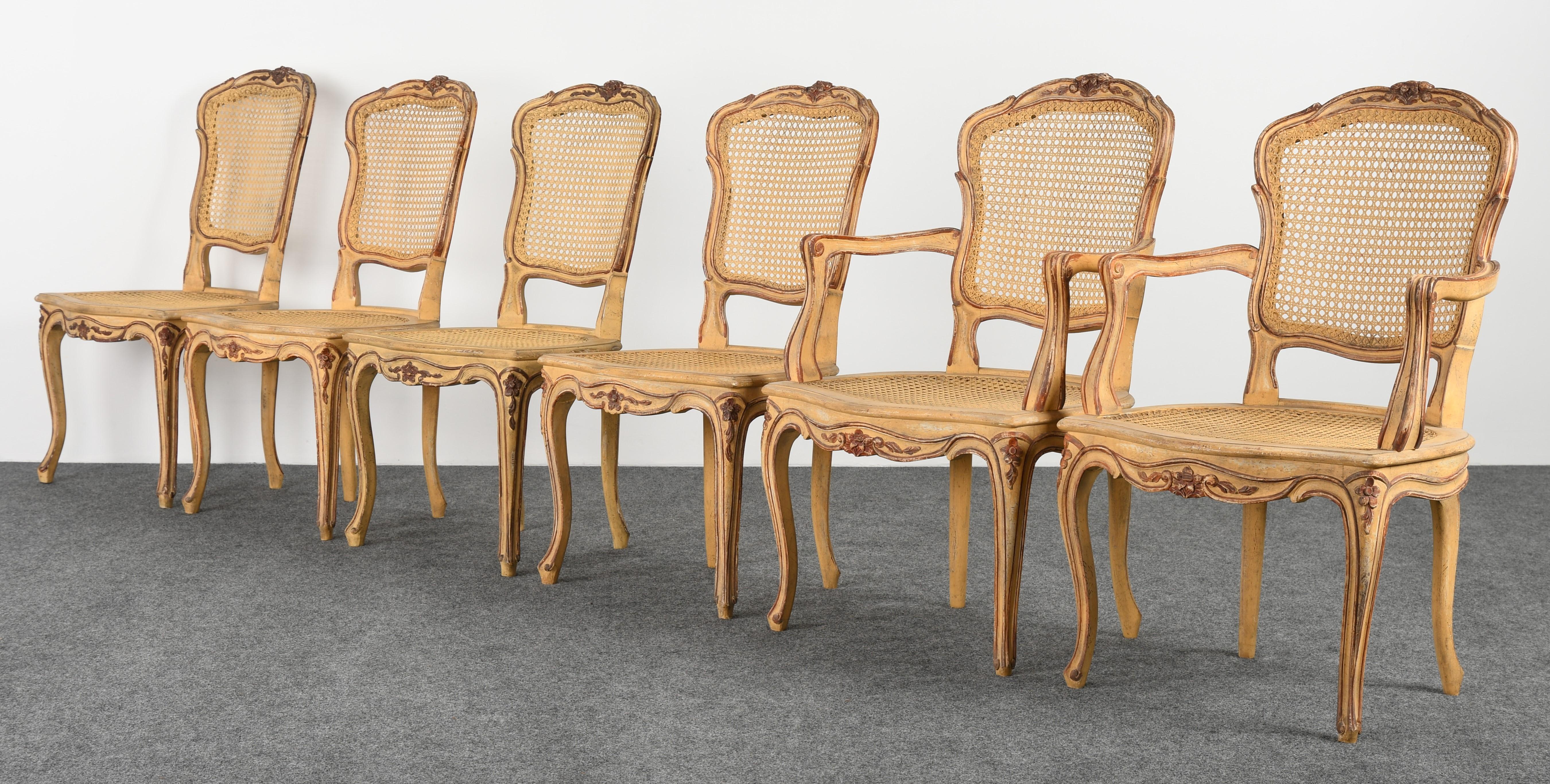 A set of six Louis XV French dining chairs with cane seats. These chairs are hand carved and hand painted yellow ocher and Venetian red. The cane seats are in very good condition. The painted finish is in very good condition with age appropriate