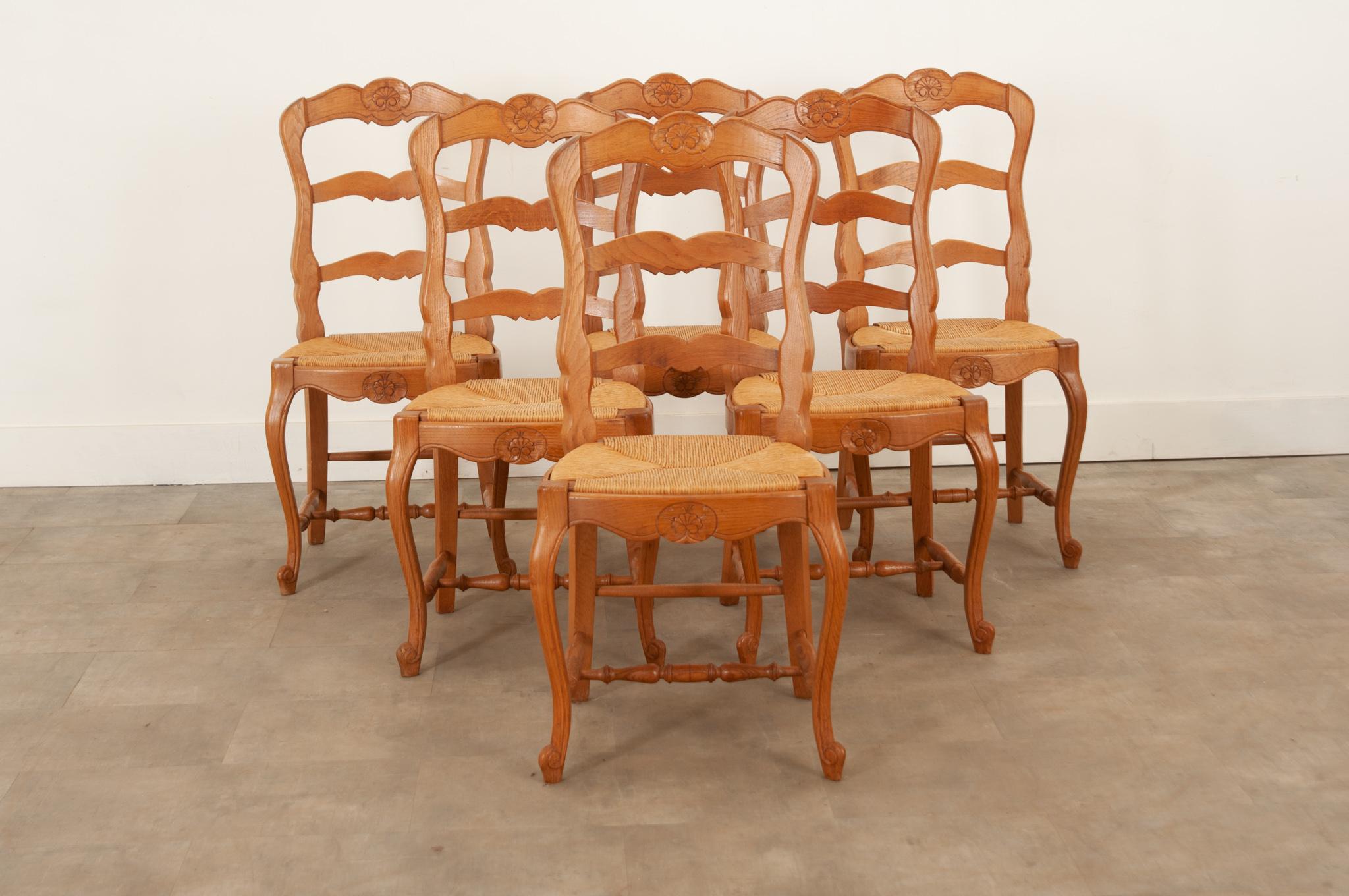A charming set of 6 dining chairs crafted using solid oak with removable rush seats. The seat backs are carved with a wonderful shell motif and nicely shaped rungs. The rush is in good used condition and continues to be comfortable. Cabriole legs