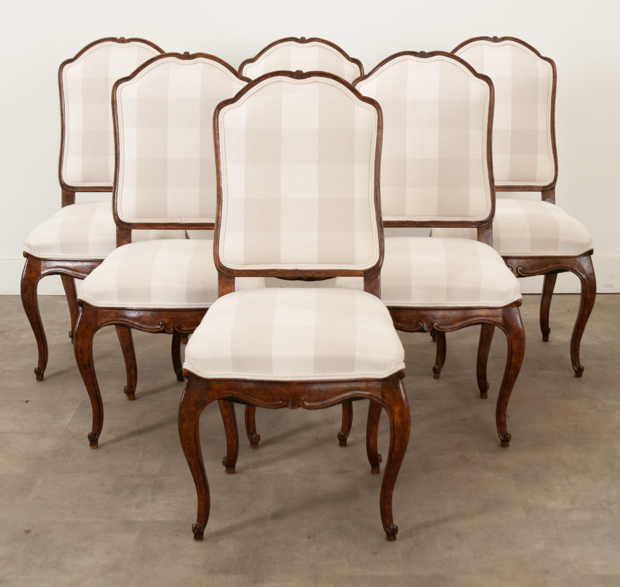 A charming set of six vintage reproduction dining chairs, made towards the end of the 20th century, in France. The chairs are made of mahogany, and are upholstered with a neutral, gingham-patterned woven fabric, which is trimmed with double welt