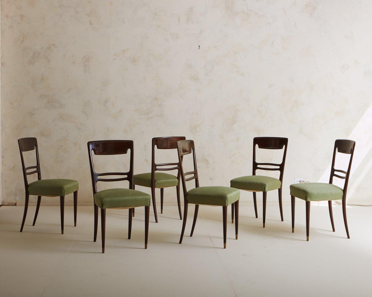 A set of 6 vintage dining chairs featuring elegant mahogany frames with tapered legs and cutout details on the seat backs. These chairs have upholstered seats and retain their original green fabric with subtle stud details. Sourced in France, 20th