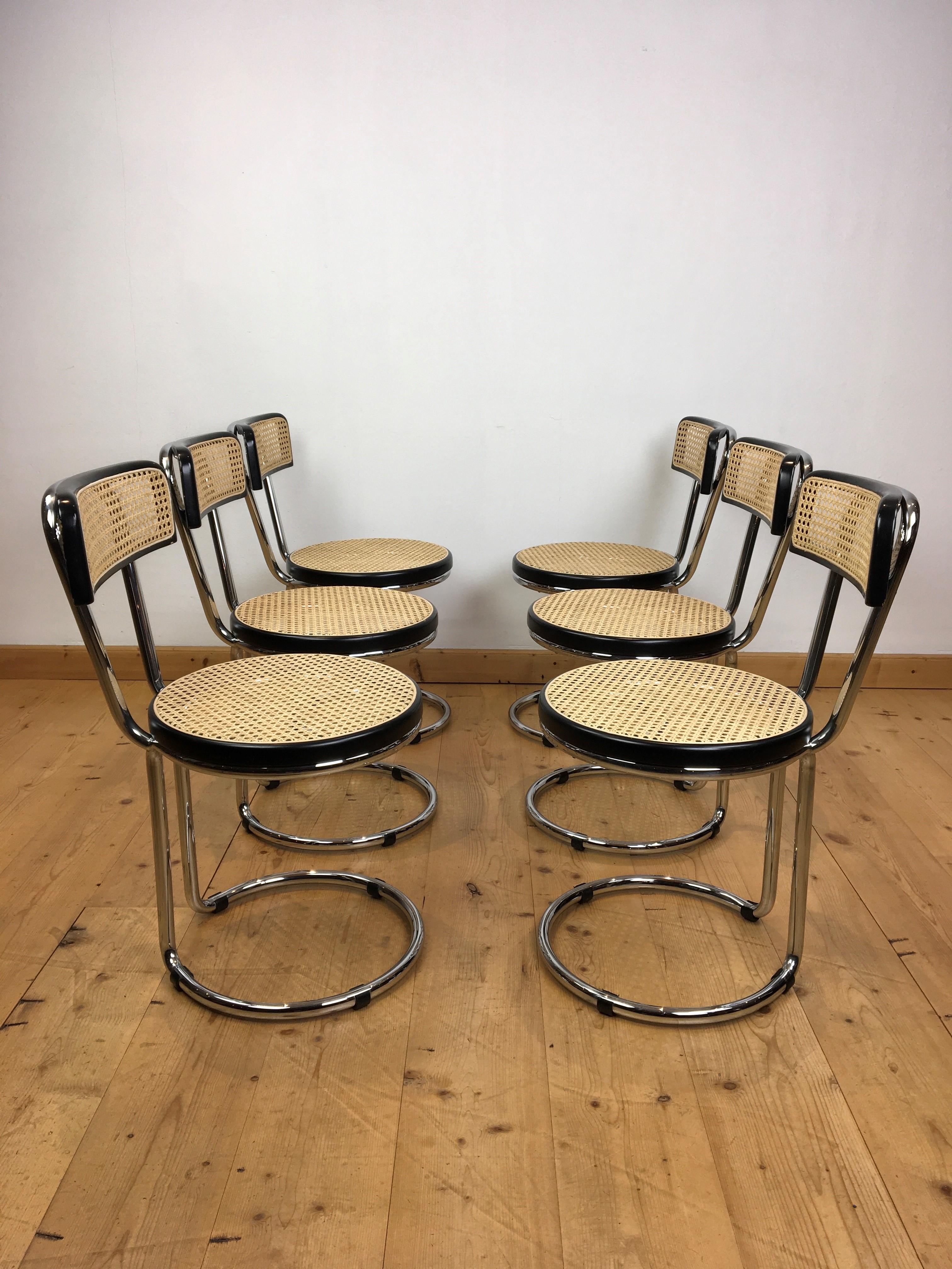 6 chairs in the style of Marcel Breuer. 
These black laquered wooden chairs have a chromed tubular frame with cane seating and are in the style of Bauhaus. They have a rounded back and also a round seating. 

All the cane from the seatings and