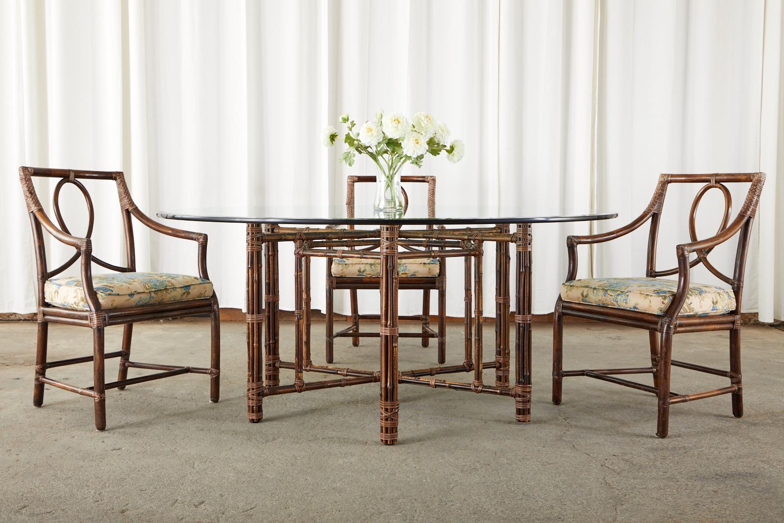 Graceful and elegant set of six loop back rattan dining chairs made in the California organic modern style by McGuire. One of their most iconic and beautiful chair designs featuring a sinuous loop back splat with a square seat back. The arms gently