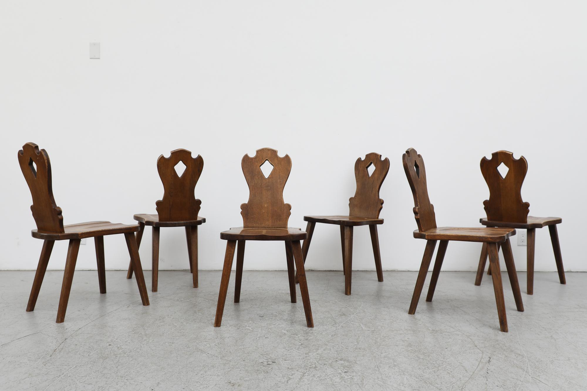 Set of 6 hand carved Brutalist solid wood dining chairs with diamond cutout. Stylistically something of a marriage between Tyrolean style ornate carving and a more sleek mid century aesthetic. In mostly original condition with some visible wear