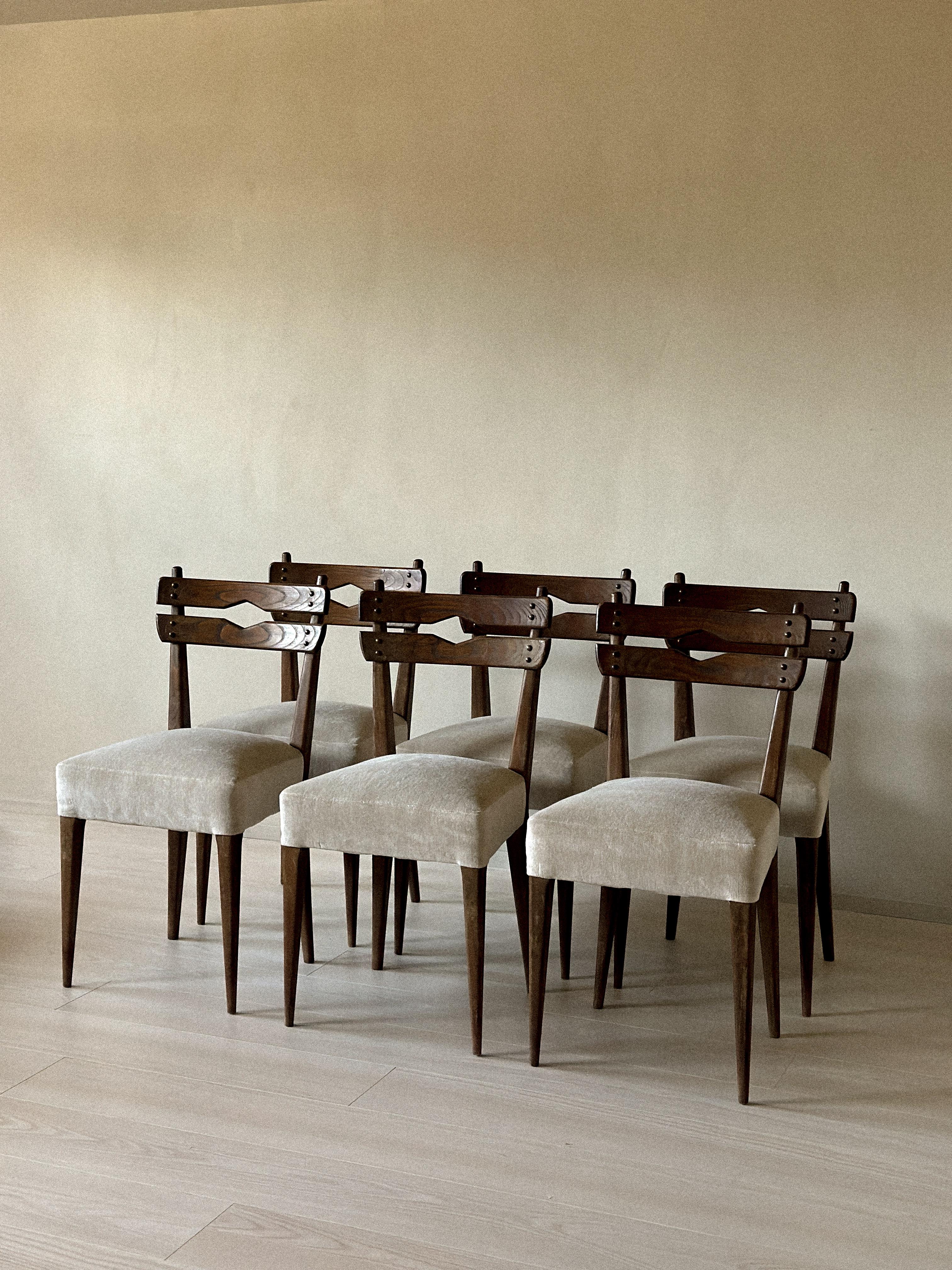 Elegantes sillas de comedor de mediados de siglo con respaldos de madera esculpida y detalles geométricos recortados. Los asientos están recién tapizados en un suave tejido neutro, que ofrece tanto comodidad como un estilo atemporal. Las patas