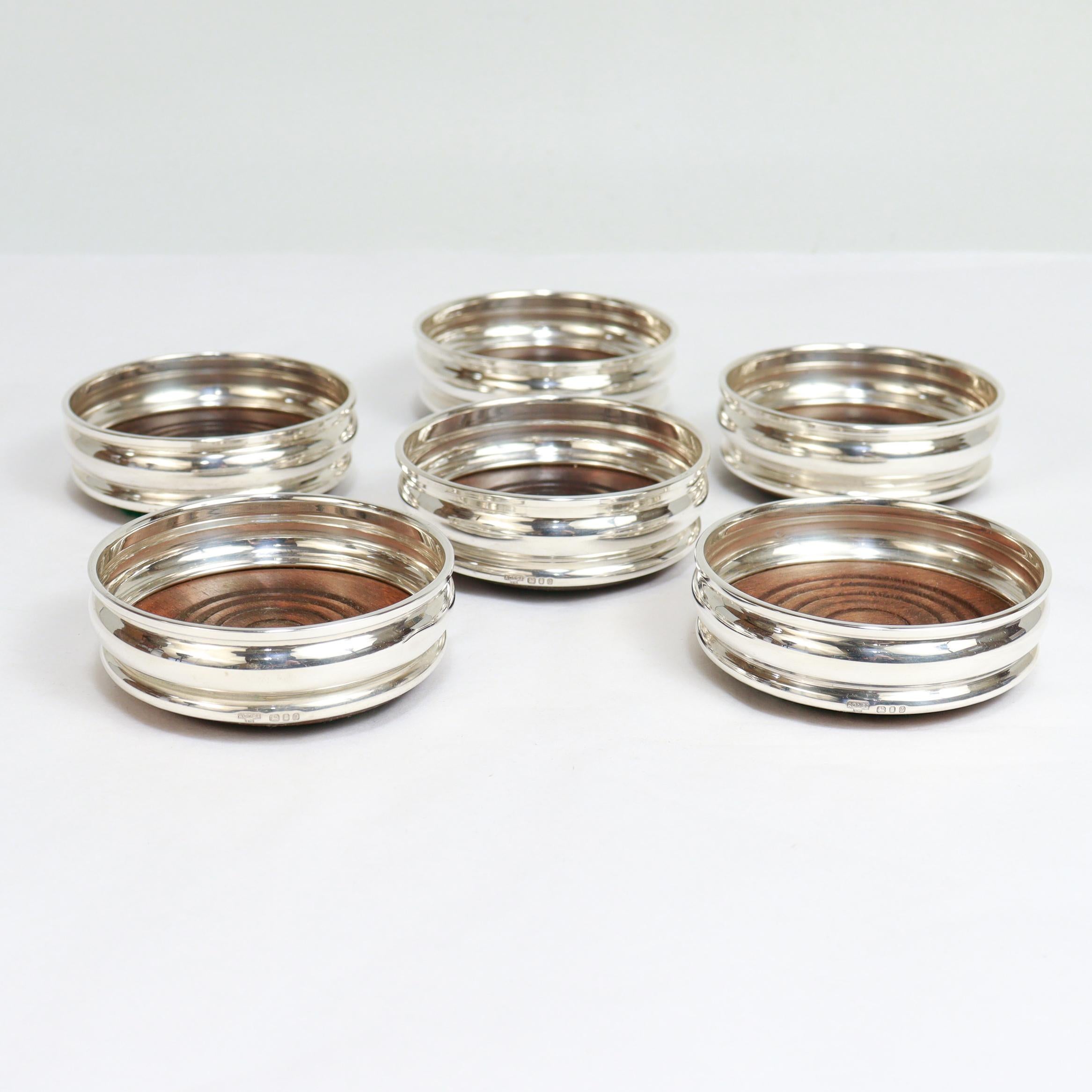 A fine set of 6 Mid-Century silver & wood cup coasters.

In sterling silver. 

By A. Chick & Sons Ltd. of London in 1971.

Each with a wooden foot, silver side, and a green felt pad to the base.

Fully hallmarked to the side of each.

Simply a