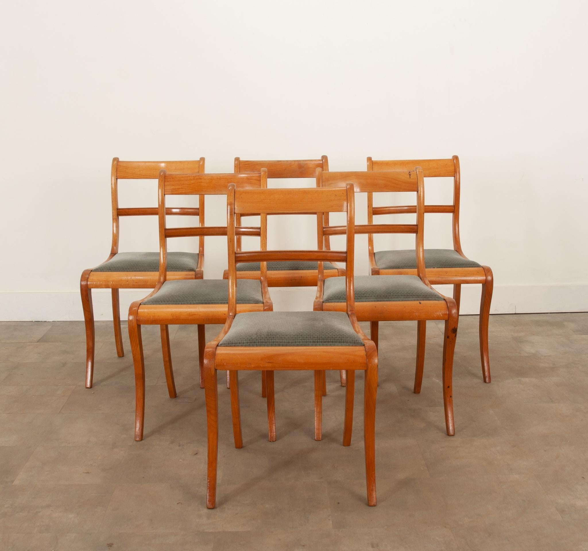 Ensemble français de 6 chaises de salle à manger de style moderne du milieu du siècle en bois fruitier massif. Toutes les chaises ont un rembourrage usé et des coussins d'assise amovibles. Les pieds en sabre évasés offrent un support stable. Toutes