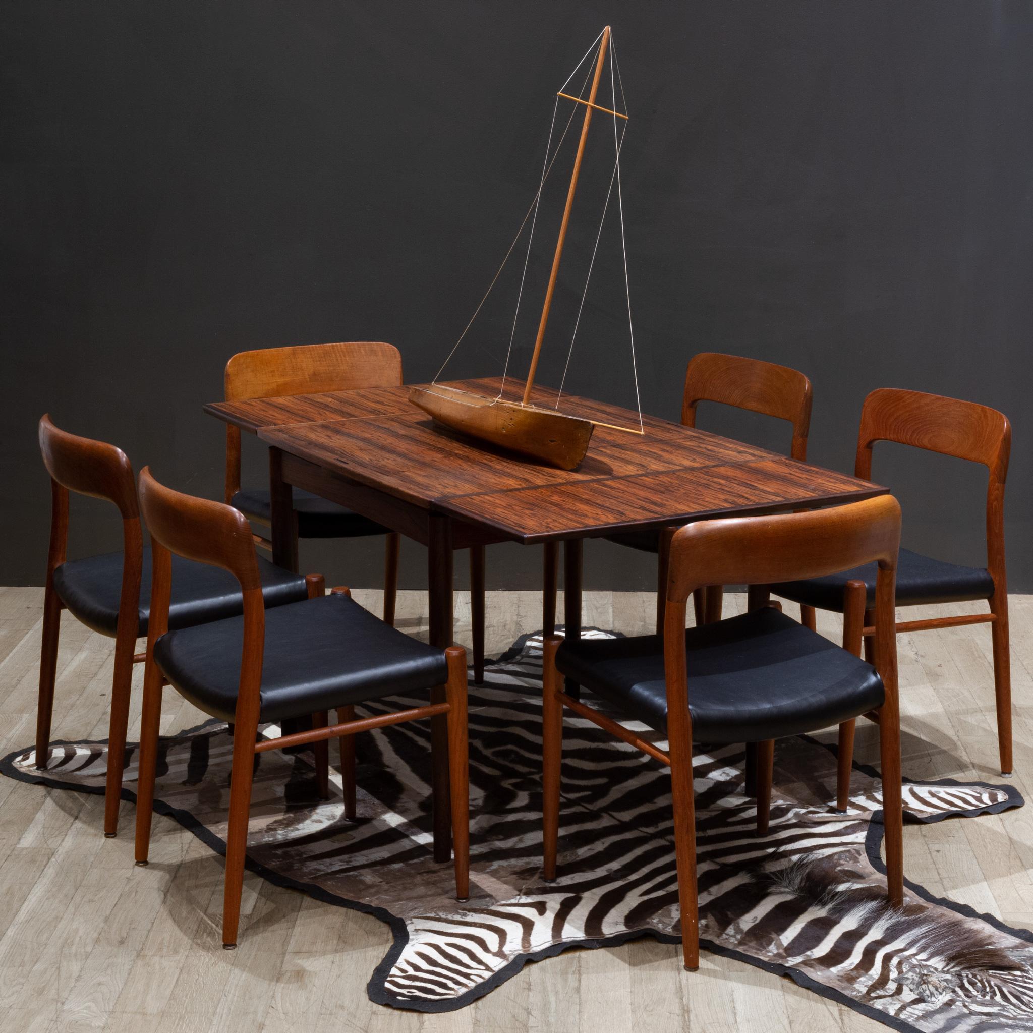 CIRCA

Un set di J.L.A. in legno massiccio di teak. Le sedie laterali Moller Model/One 75 sono state tappezzate con un nuovo vinile nero in linea con il design originale.

    CREATORE Niels Otto Moller per J.L. Moller, Danimarca.
    DATA DI