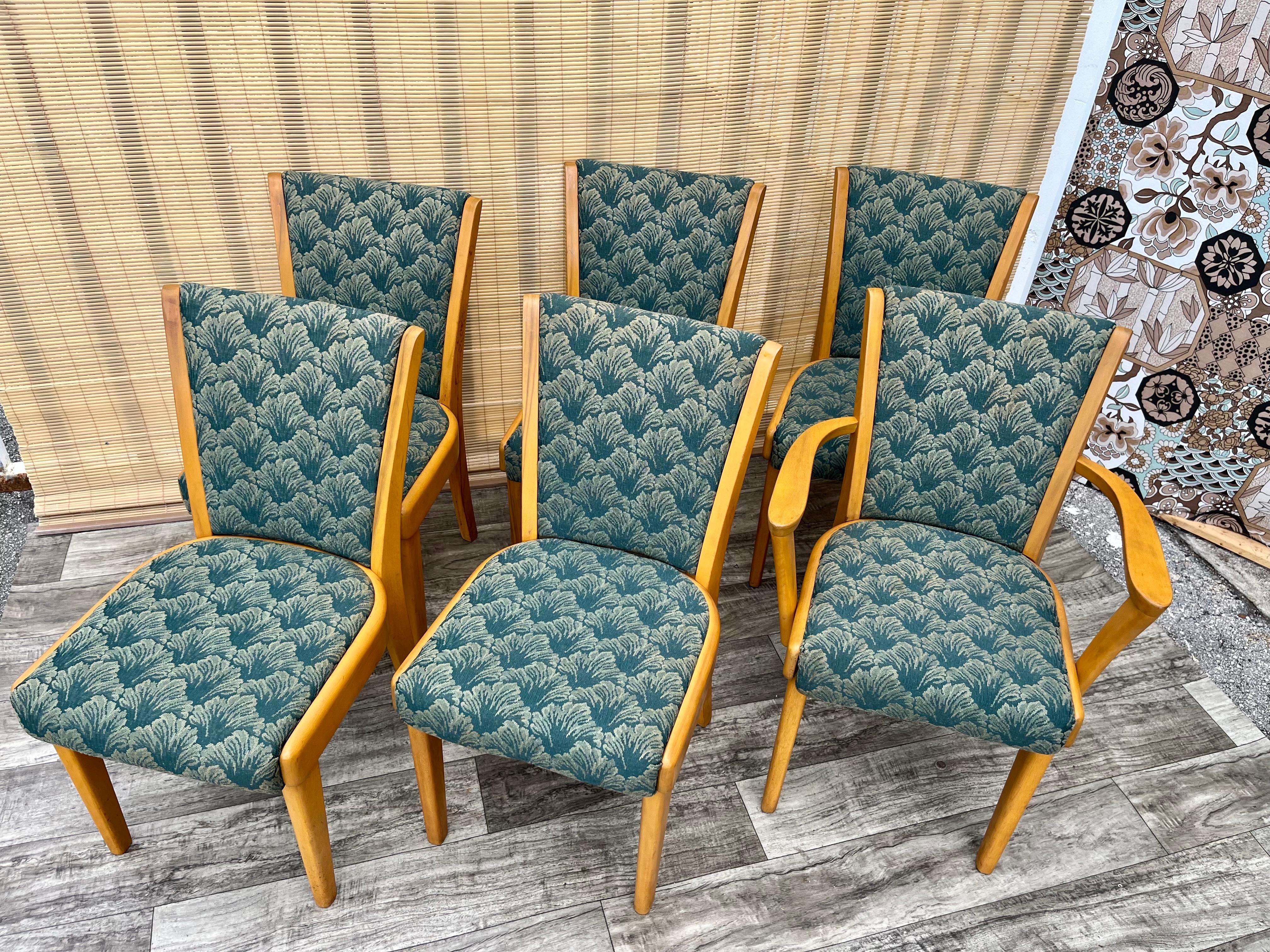 Set of 6 Mid Century Modern Heywood Wakefield Dining Chairs. Circa 1950s
Five side chairs and one captain chair.  
Good solid condition with age appropriate wear. The upholstery is also in good vintage condition with some signs of wear consistent
