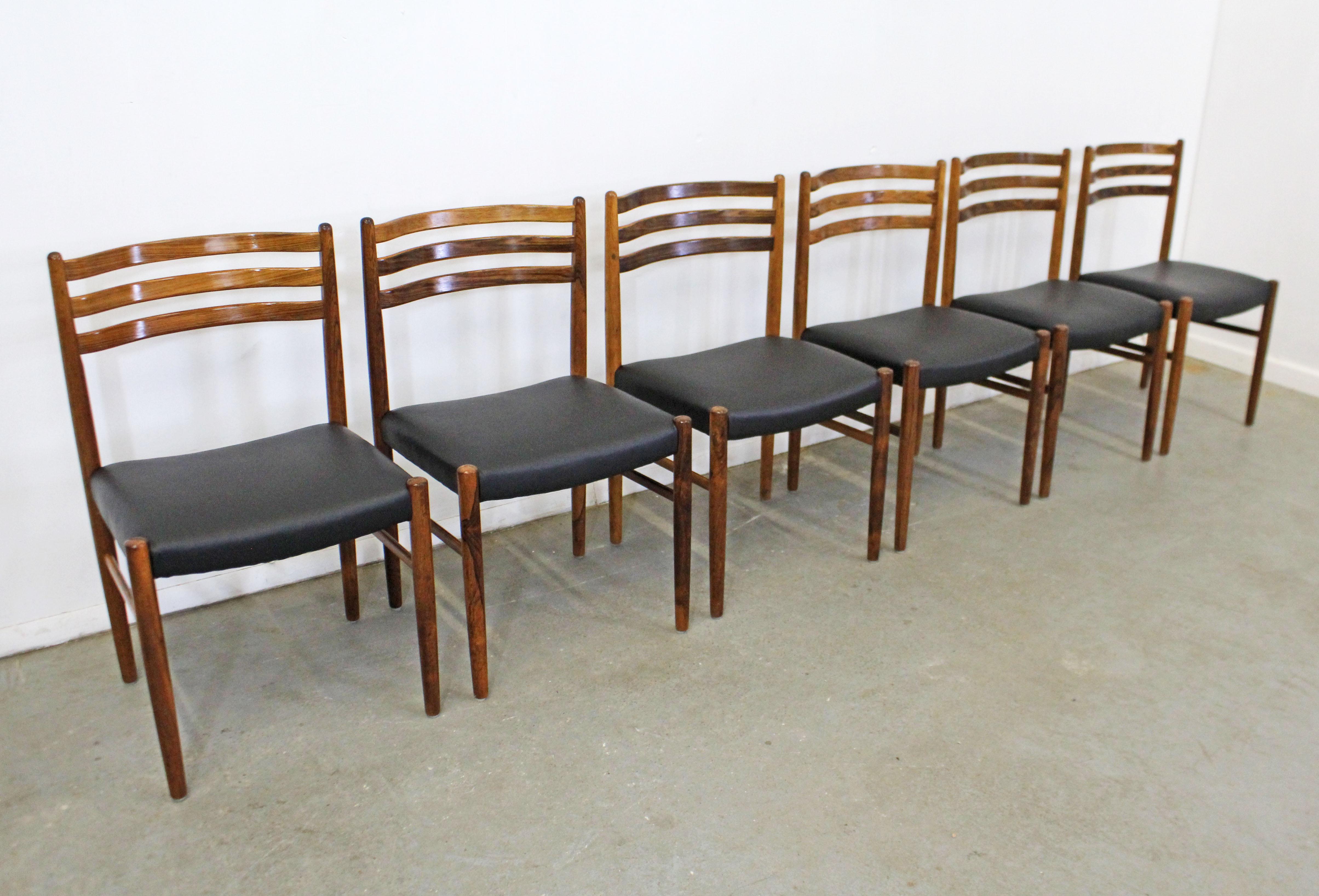 What a find. Offered is a vintage Mid-Century Modern set of rosewood dining chairs. These chairs have a beautiful rosewood grain and have been reupholstered with black leather. They are in good condition with some surface wear/scratches on the wood.