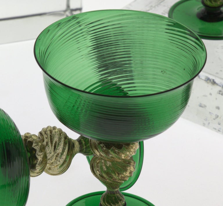 Set of 6 stemmed cups in green with dense rigadin deep cups. Stem is solid glass with gold leaf fused in the rigadin design. Stem hot attached to cup and foot with two green necks. Foot disc has an eleant reverse lip.

There are a few iron marks