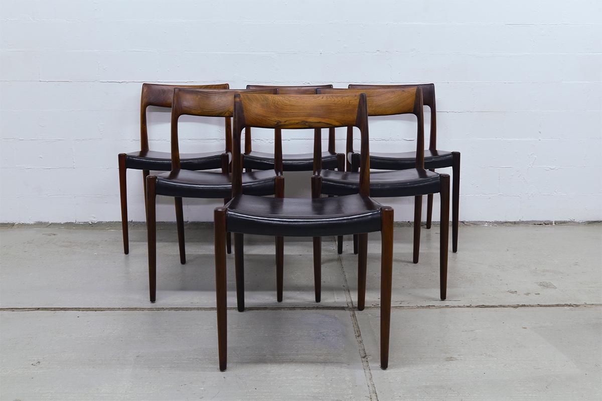 Set of 6 rosewood dining chairs model 77 designed by Niels Moller and manufactured by J.L. Møller Mobelfabrik. These chairs are made of solid rosewood wood and have the original black leather seats with some light patina. The chairs are in very good
