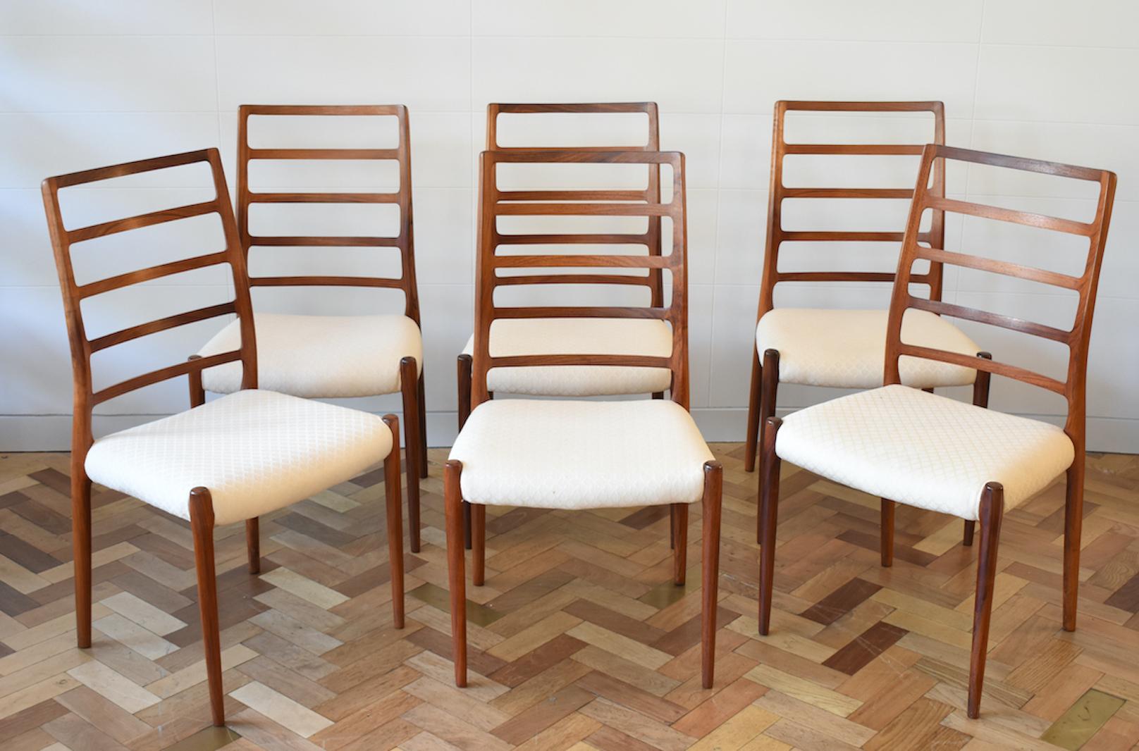 Gorgeous set of six Model 82 rosewood dining chairs designed by Niels O. Møller for J.L. Møllers Møbelfabrik in Denmark, circa 1970s. These rosewood chairs feature the distinctive curved ladder back and tapered legs, offering both comfort and