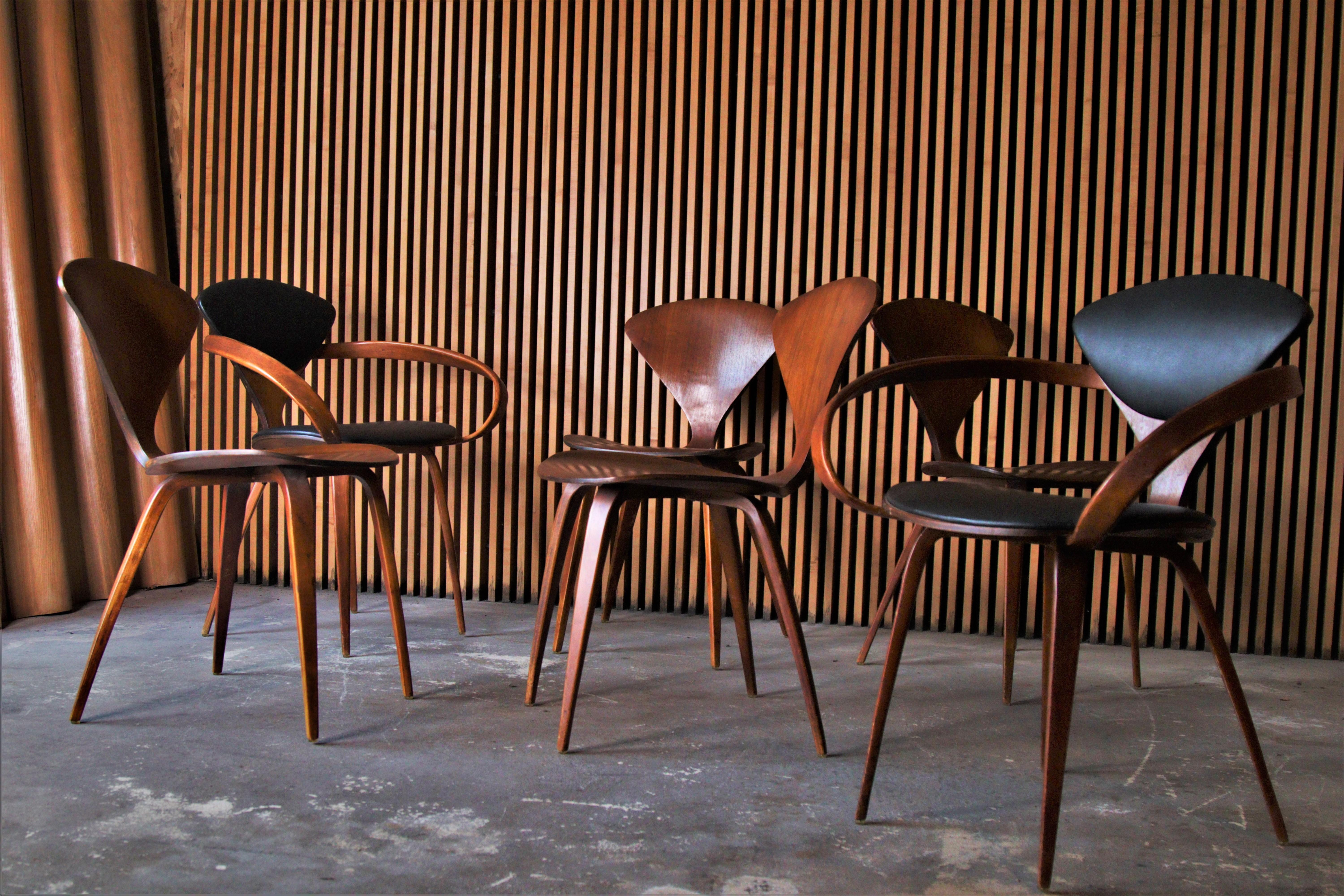 A set of 6 Pretzel dining chairs designed by Norman Cherner for Plycraft. The set consists of two armchairs with black leatherette upholstery and 4 upholstered walnut side chairs.

Dimensions:
Armchairs 31