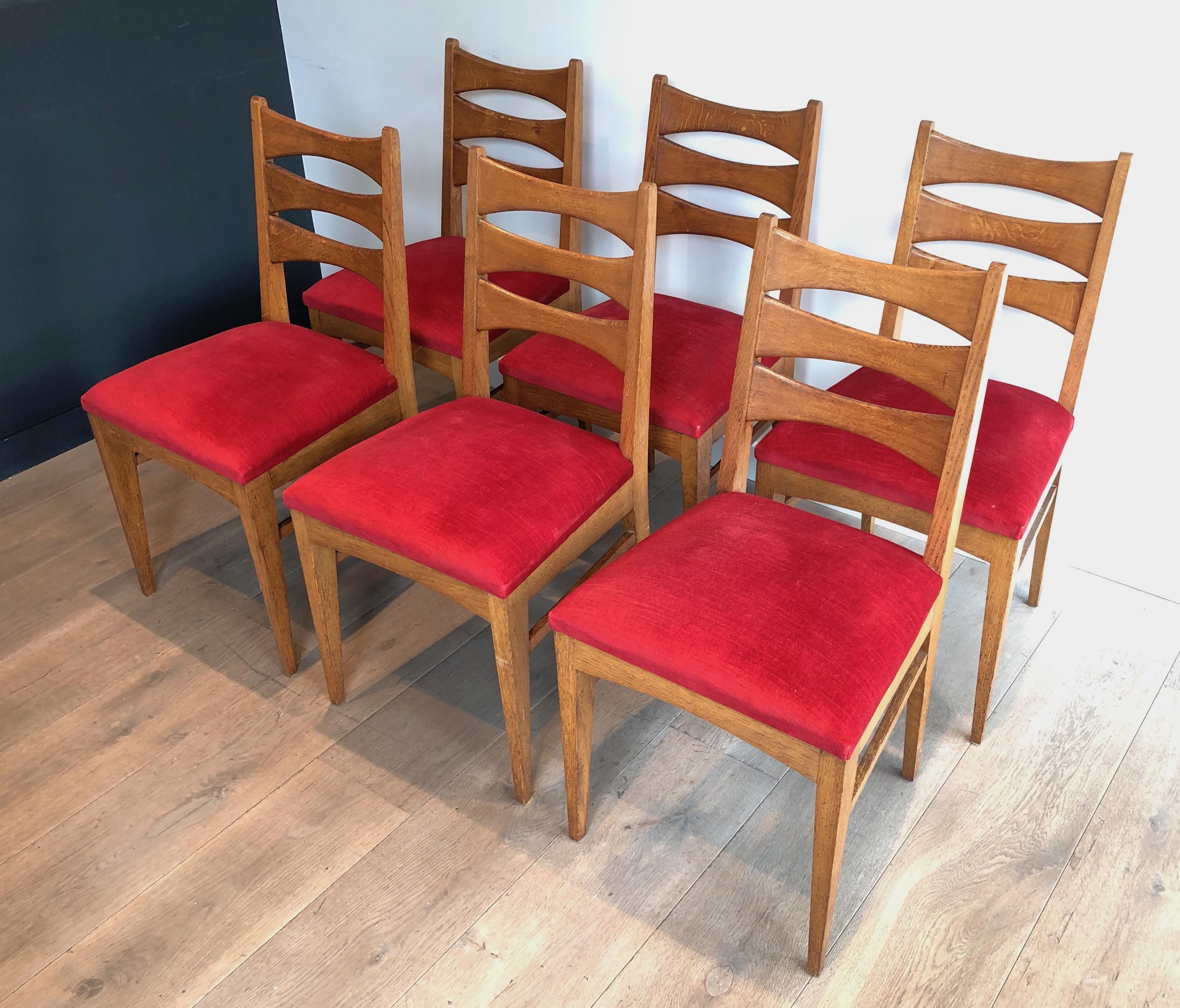 This very nice set of 6 chairs is made of oak with red velvet seats. The design is very interesting and typical from 1950's French Work. Circa 1950.
