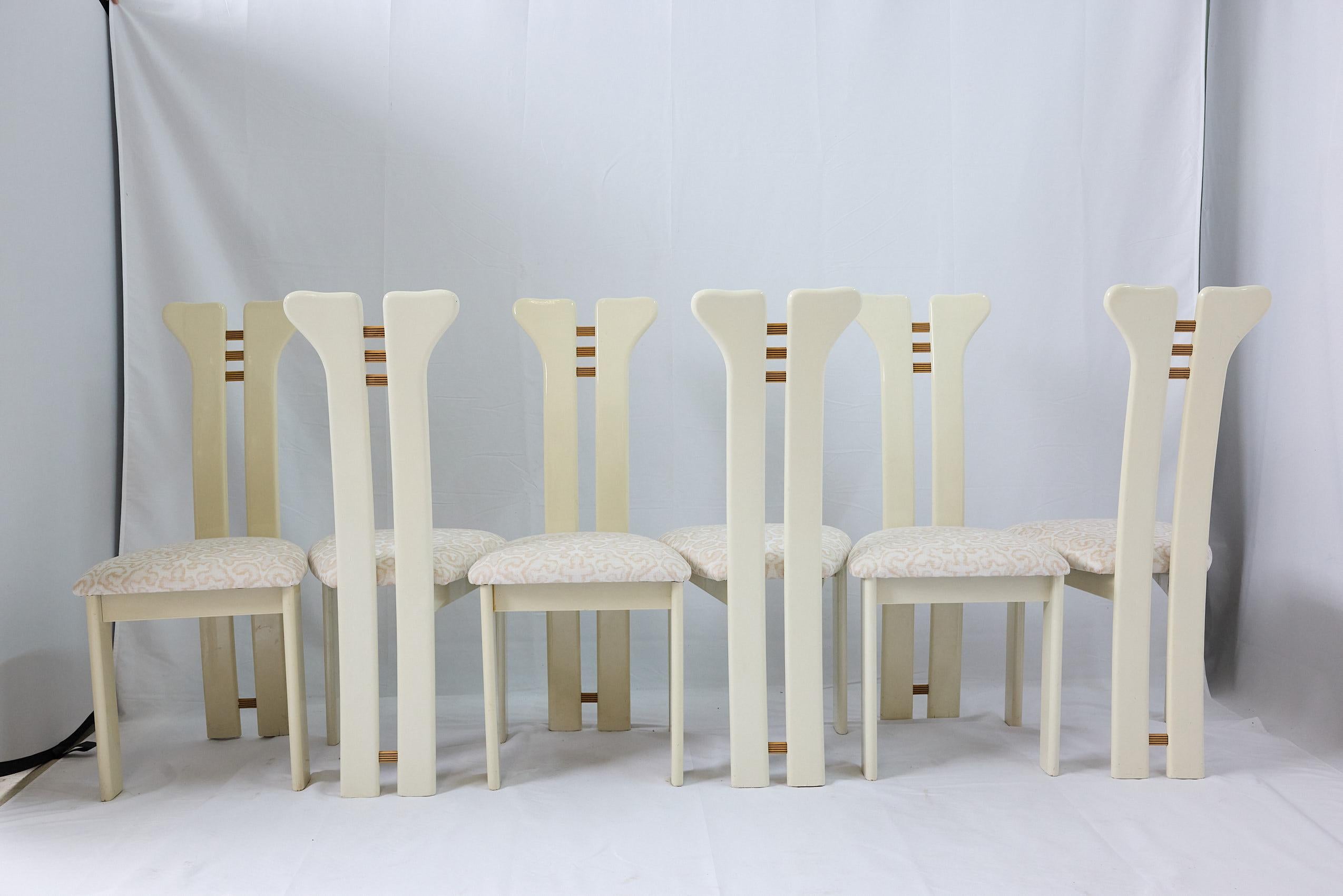Ensemble de six chaises de salle à manger sculpturales post-modernes Pierre Cardin en laque blanche avec de hauts dossiers fendus et des attaches en bois contrastées. Les chaises ont été retapissées dans un tissu neutre de Jim Thompson. Vers 1980.