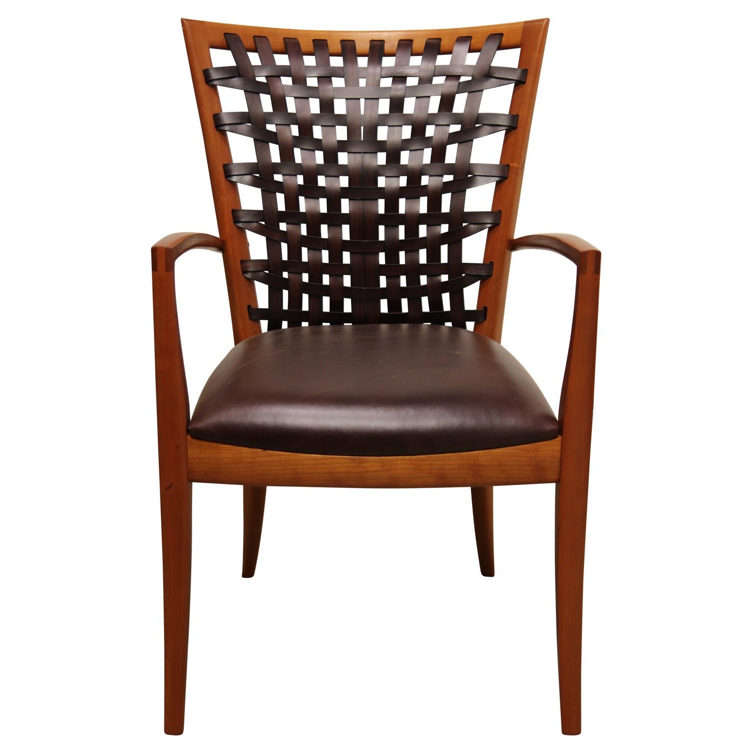 Unique sculptural designed dining chairs made from cherrywood and leather. The chairs were designed and made by Texas furniture maker, Roger Deatherage. The chairs feature a woven leather back providing adjustable support with ventilation, and