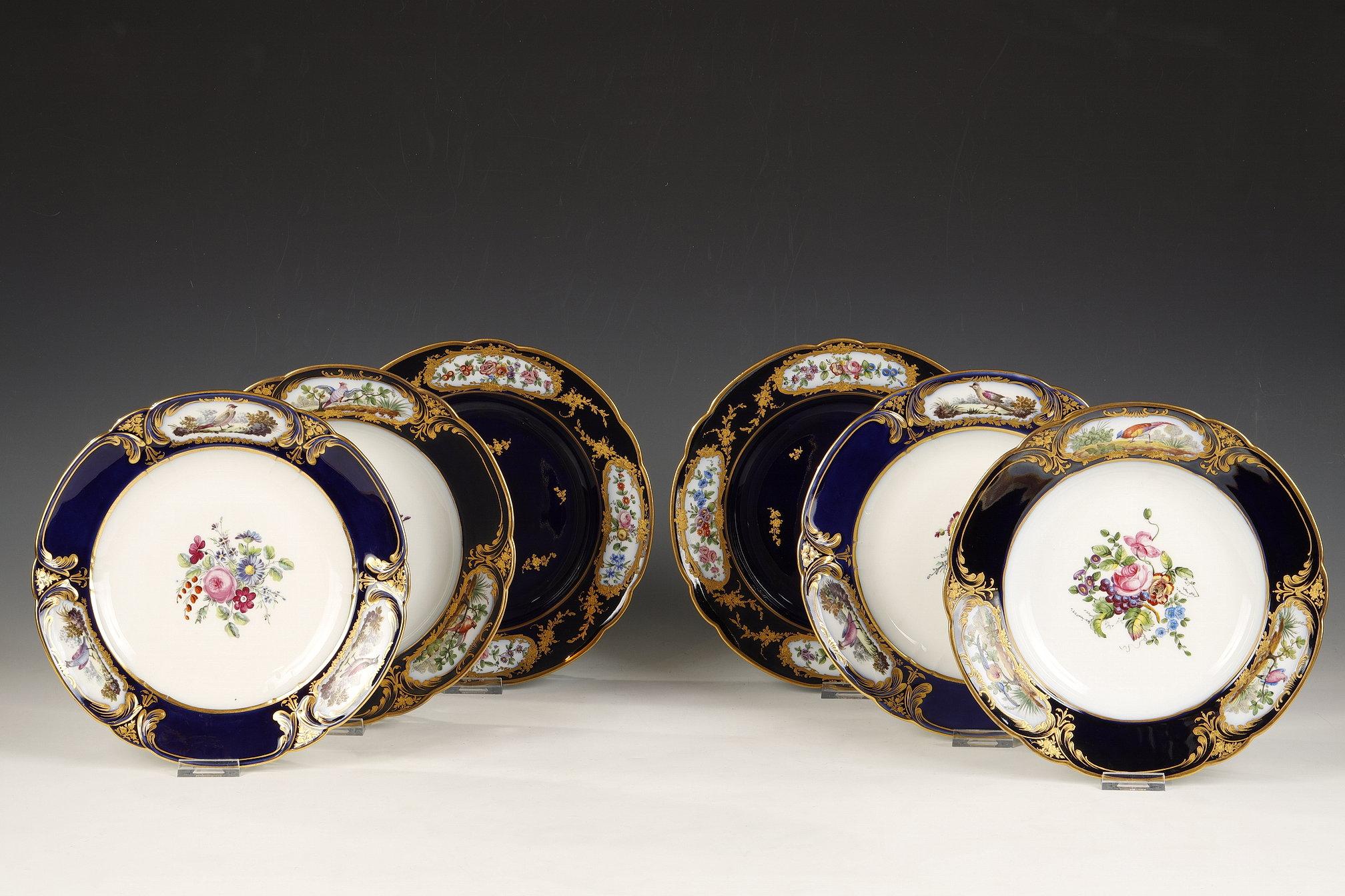 Beautiful set of six porcelain plates, comprising two plates decorated in the center with golden branches on a gros bleu background, and adorned on the border with four bouquets of polychrome flowers in flowery oval gilt cartouches, and four plates