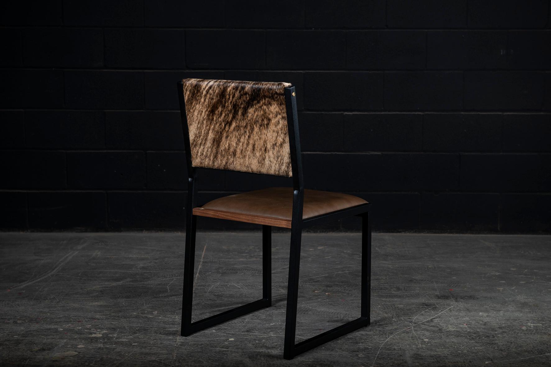 The shaker chair is handcrafted to order from our unique Ambrozia black textured steel tubing frame with a genuine leather seat and Cowhide back. Featuring subtile solid wood insertion that will give a warm and distinguished touch to your space.
