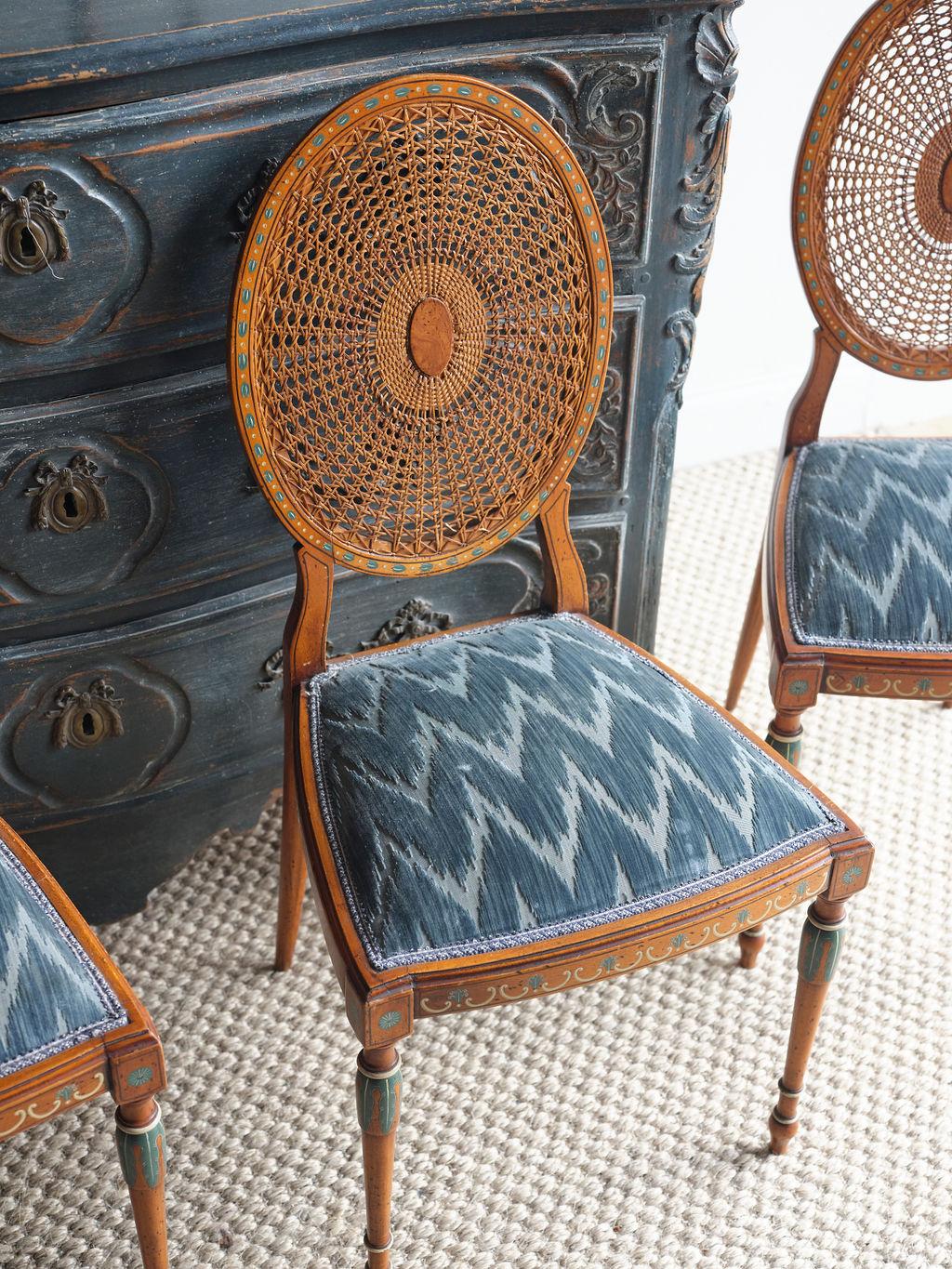 There simply are no other dining chairs out there like this set of 6 Sheraton style chairs. Featuring oval cane backs, chevron patterned blue and white fabric seats, and hand-painted details on the wood sections. There are 2 armed end chairs, and
