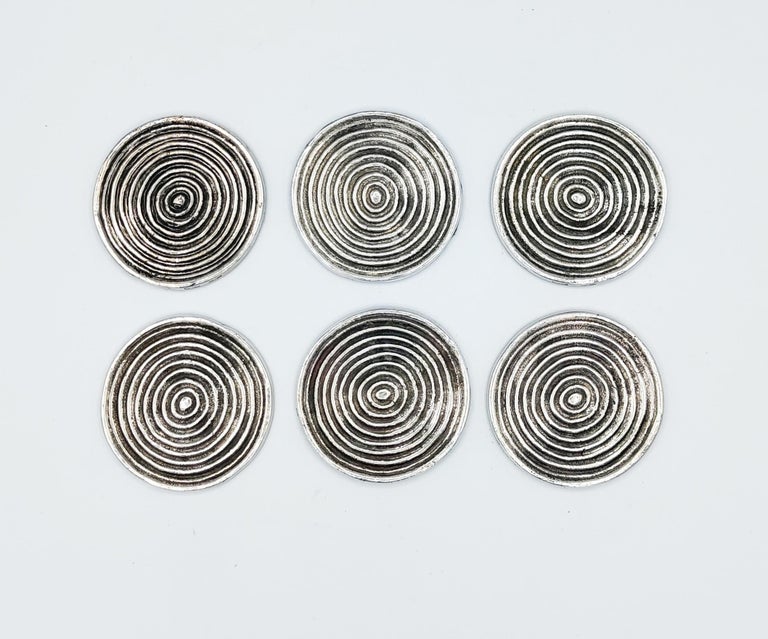 Beautiful and rare set of 6 silver metal coasters manufactured by Valenti in Spain in 1970s. Incredible work of quality with a heavy silver metal with a spiral screw , and on the over size a beautiful brown leather.
