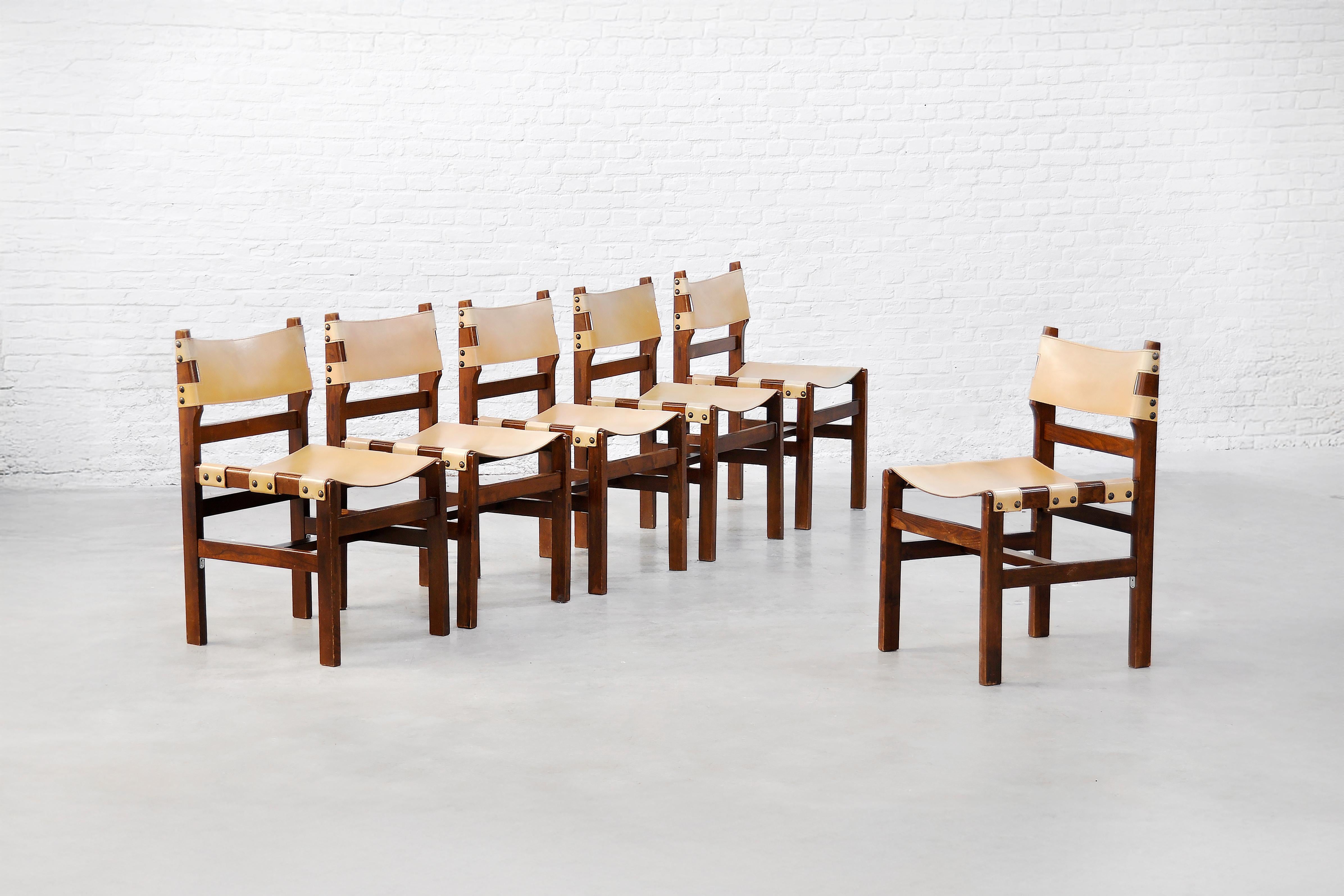 A set of six dining chairs by Maison Regain, crafted in France during the 1970s. These chairs feature solid stained elm frames with clean lines and a warm wood tone, highlighting the natural grain. The seats and backrests are made of high-quality