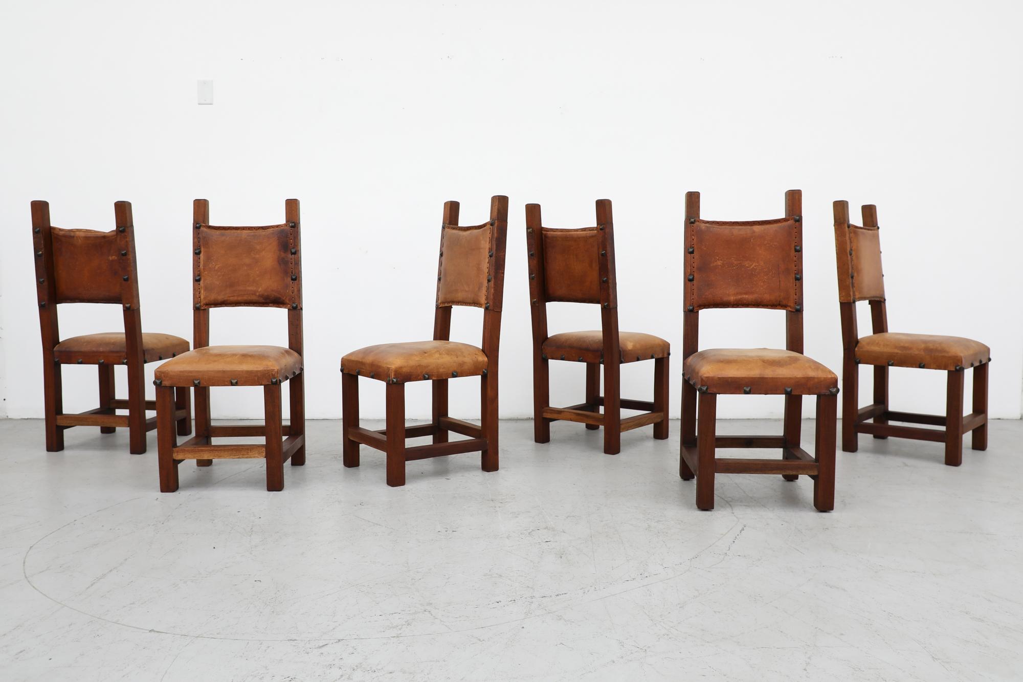 Set of 6 Mid-Century Spanish style Brutalist dining chairs. Leather seat and back rest on heavy wood frames with leather weaving detail and iron pyramid stud accents. In impressive original condition with some wear and visible patina consistent with