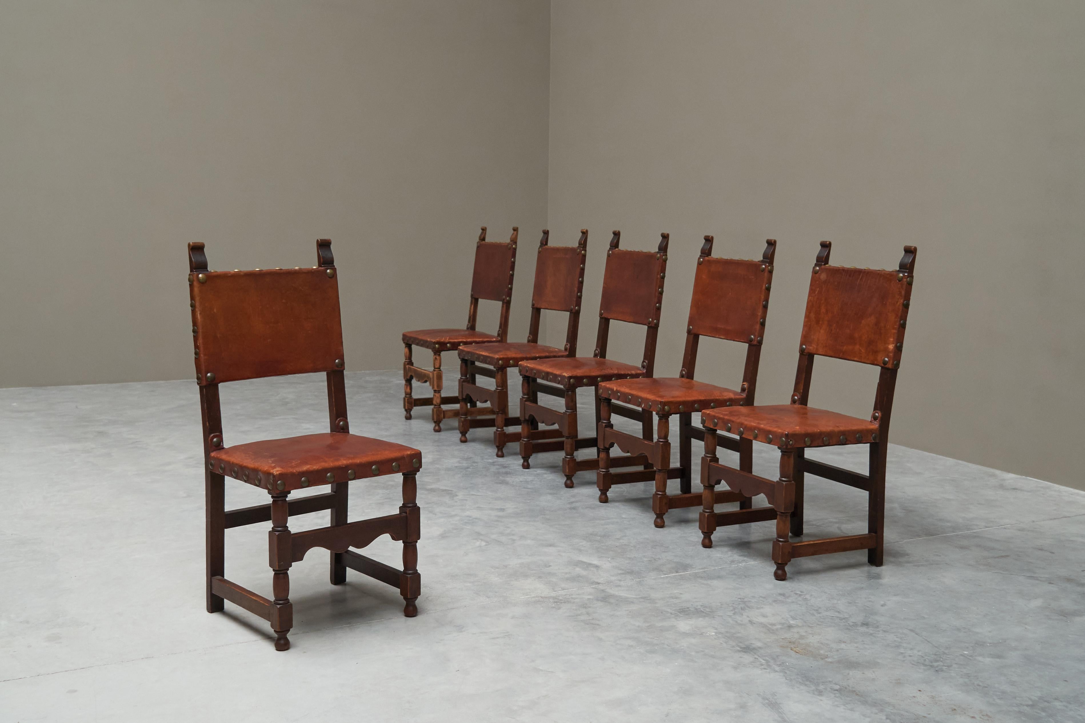 Set of 6 'Spanish' Chairs in Solid Oak, Leather and Brass, Europe, mid 20th century,

This is a stylish and distinct set of 6 dining chairs in solid oak, patinated leather and brass.

These chairs feature a very distinct and particular design after