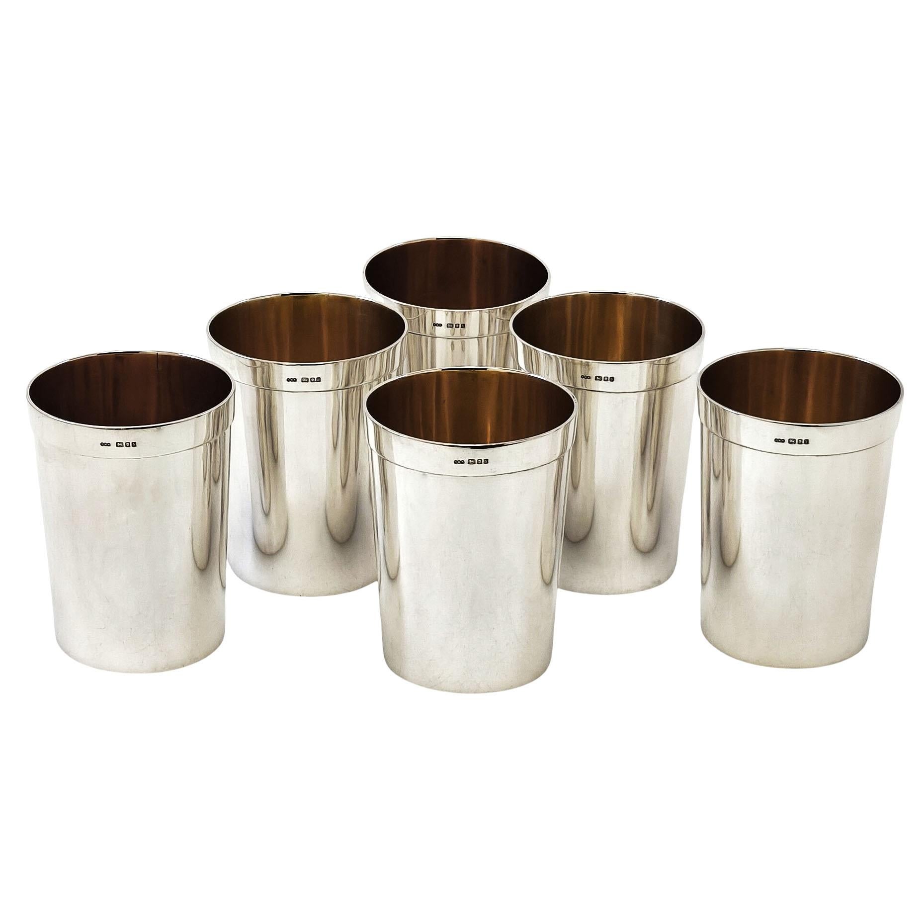 Un set di 6 bicchieri in argento massiccio con un design elegante e sobrio dai lati dritti e affusolati. Le coppe d'argento hanno una fascia liscia lungo il bordo superiore e sono lucidate all'esterno. L'interno di ogni bicchiere d'argento è