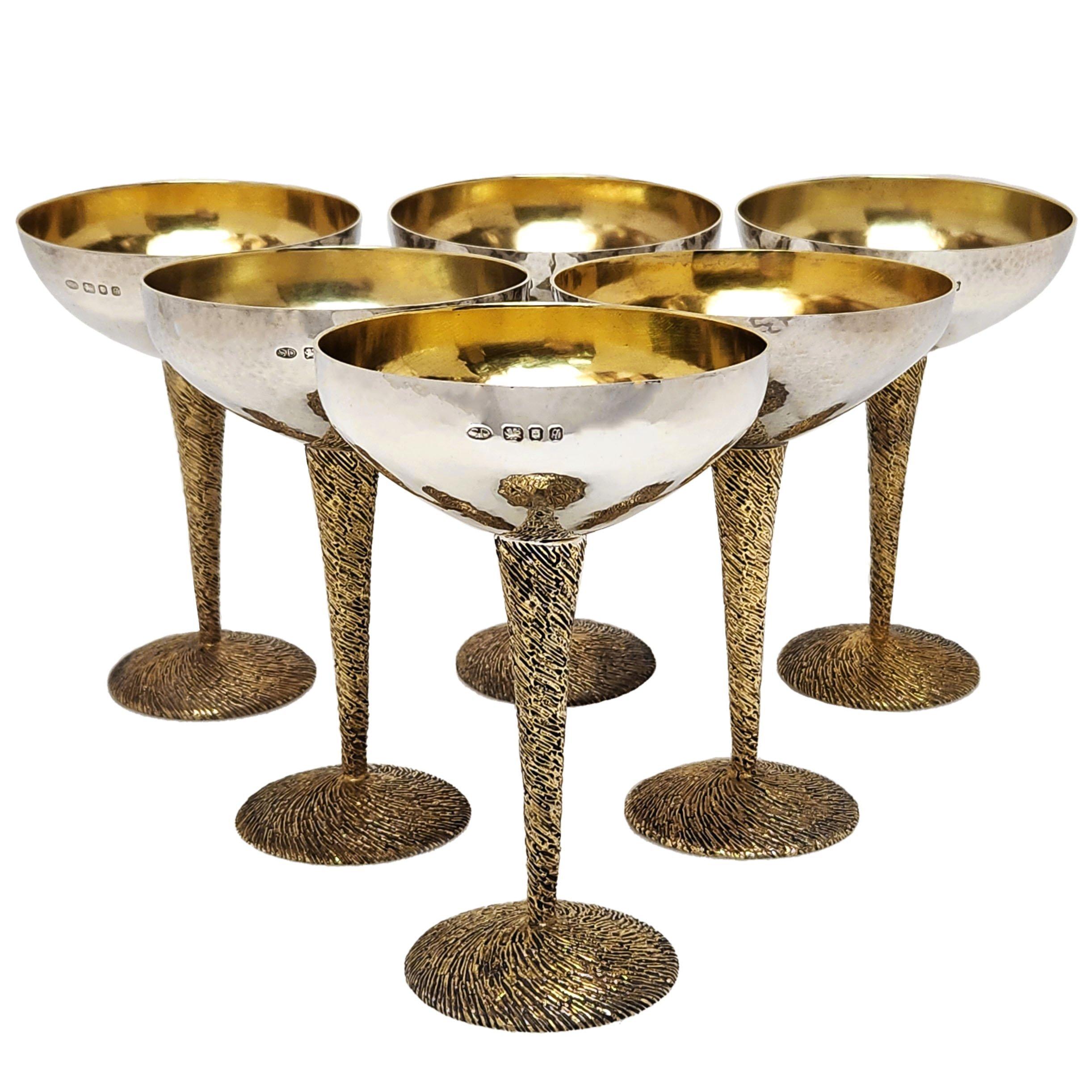 Un favoloso set di coppe da champagne d'epoca in argento massiccio, realizzate dallo stimato argentiere Stuart Devlin nel suo stile caratteristico che fonde il classico argento lucido con abbellimenti dorati in pacchi. La ciotola di ogni Coupe è in