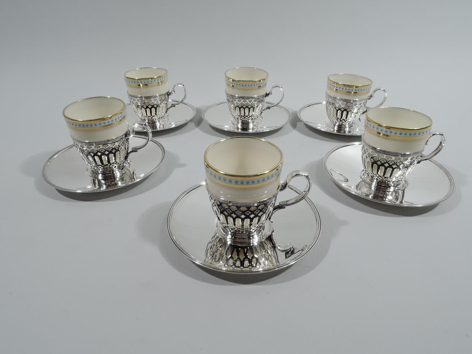 Set of 6 Edwardian sterling silver demitasse holders and saucers. Made by Tiffany & Co. in New York, ca 1909. Each holder: tapering sides with pierced geometric ornament, capped and high-looping double-scroll handle, and reeded rims. Each saucer:
