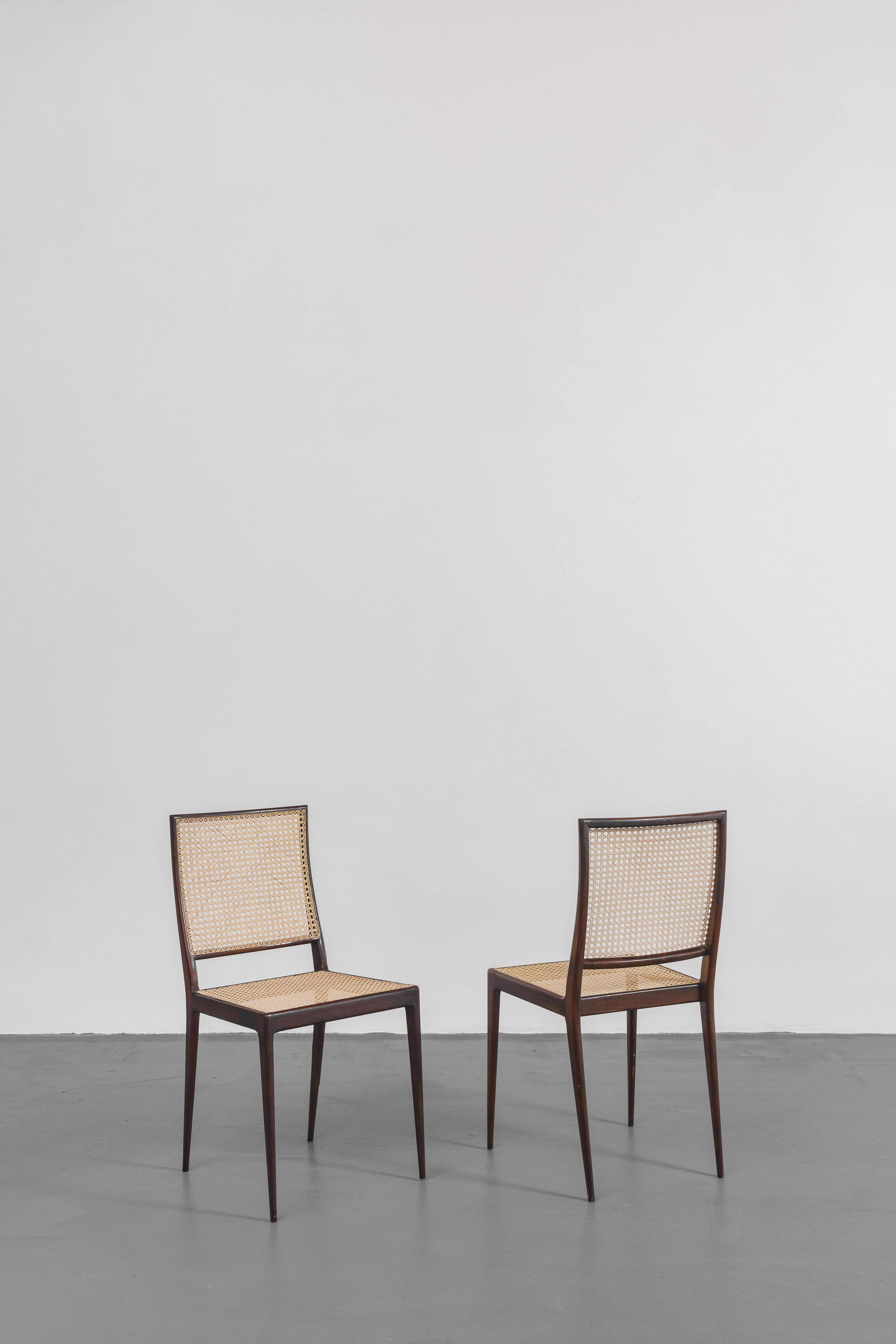 Cet incroyable ensemble de six chaises conçu par Geraldo de Barros (1923-1998) et fabriqué par Unilabor a une structure en bois de rose massif avec des dossiers et des sièges en canne. Parce qu'il s'agit d'un matériau moins dense, le tissage délicat