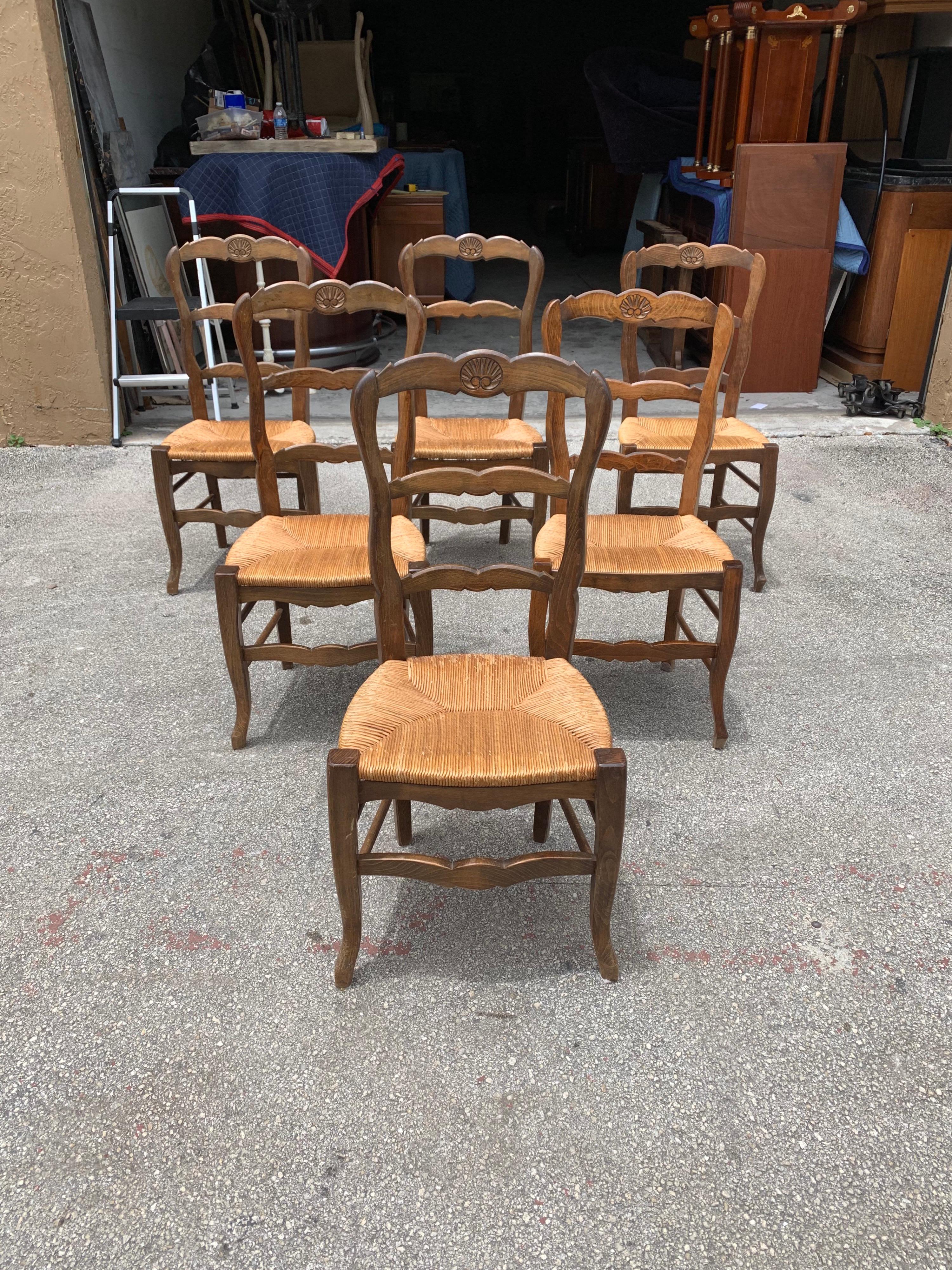 Set of six French country chairs solid walnut circa 1910s, original rush seats are in very good condition, the 6 dining chair frames are in excellent condition, we travel to buy all our pieces in France. The chairs are solid and very sturdy.