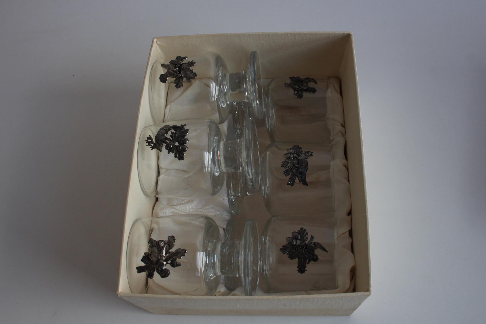 Feiern Sie den Geist der Jagd mit diesem charmanten Set aus sechs Vintage-Glasbechern, die jeweils mit einem detaillierten Zinnemblem verziert sind, das traditionelle Jagdmotive wie Hirsche, Vögel, Hunde und Waldszenen zeigt. Diese wahrscheinlich in