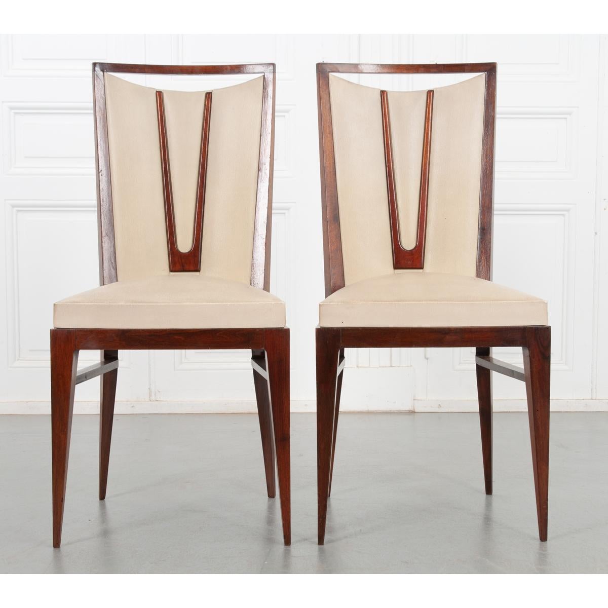 This delightful set of 6 dining chairs have a sleek design with comfortable upholstery. The rich color of the wood frame contrasts well with the light fabric. A cut out in the slightly curved seat back creates a pleasing illusion. Straight, tapered