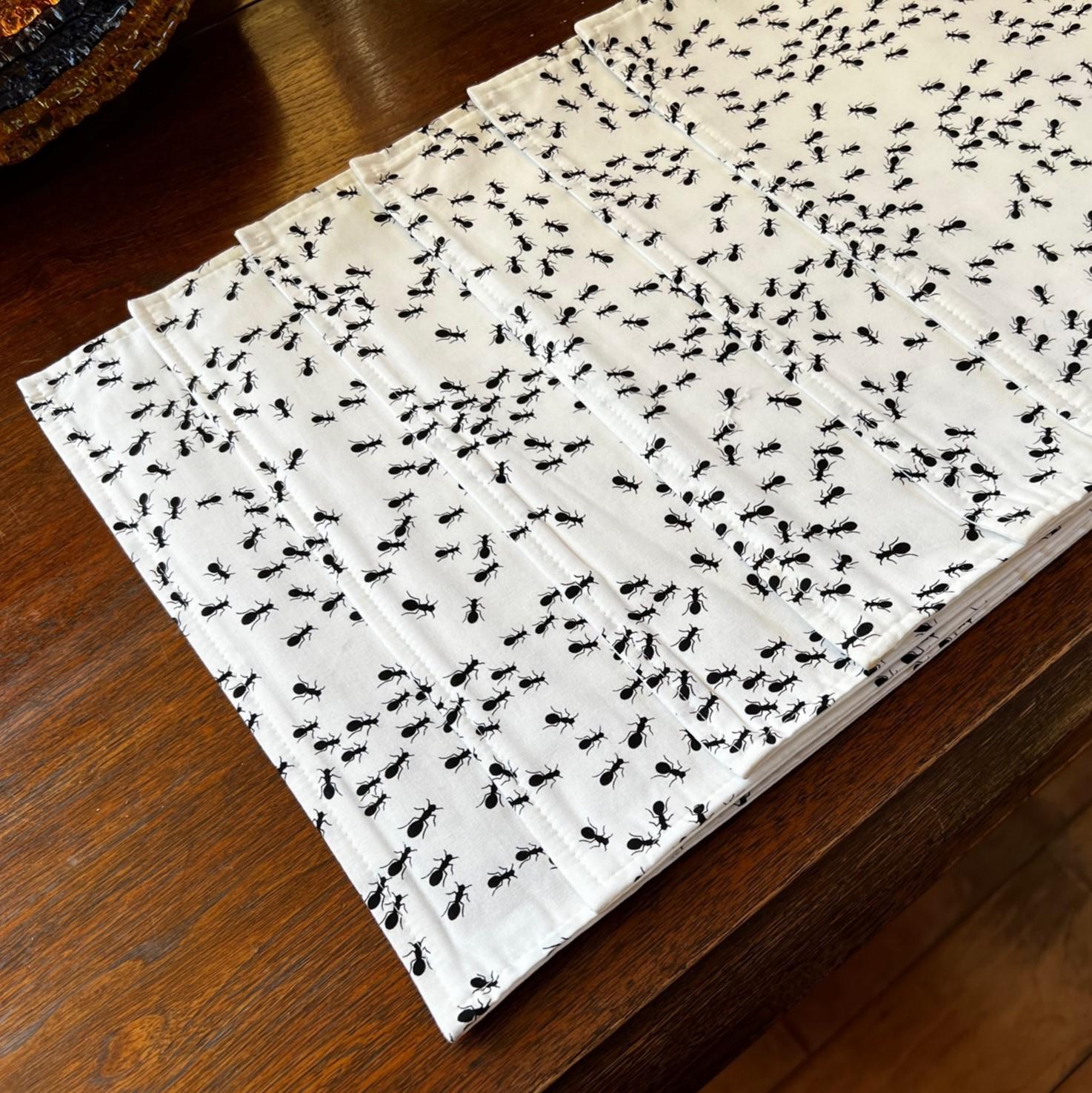 21st c. American, a set of 6 cotton placemats. White background with an army of printed black ants marching all over.

Dimensions:
17