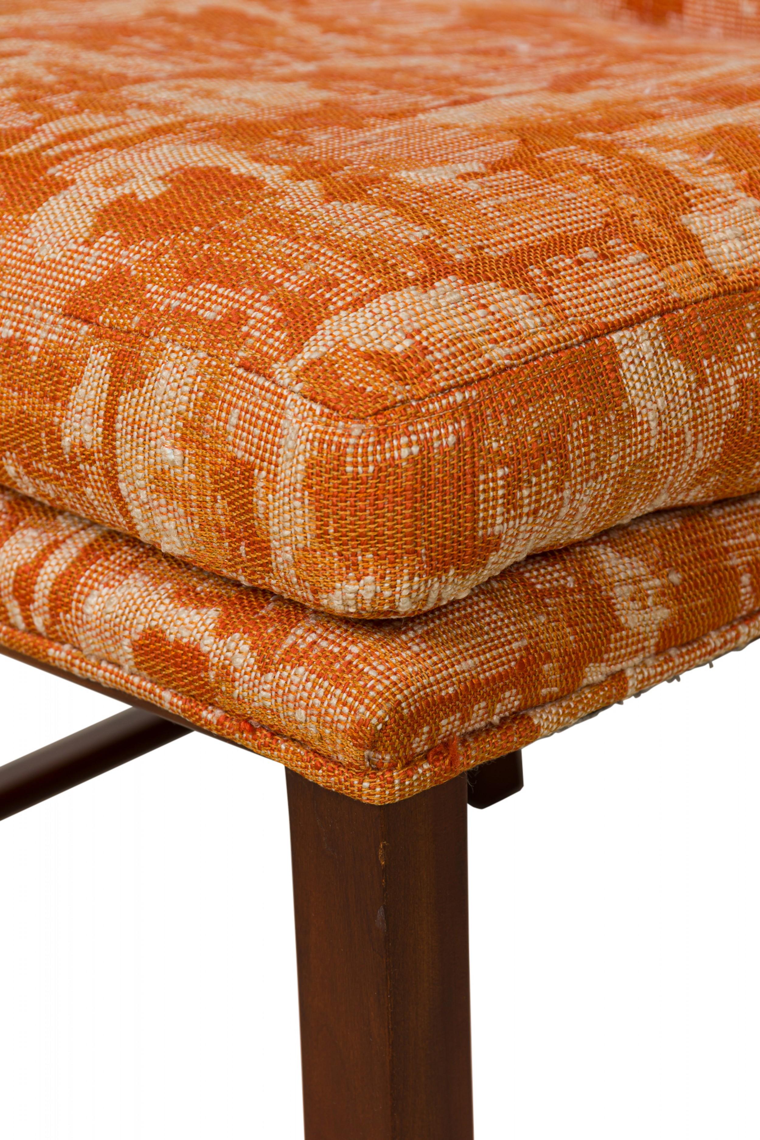 Set di 6 sedie da pranzo in legno di forma rettangolare della metà del secolo scorso con sedili e schienali leggermente inclinati, rivestiti in un tessuto astratto beige/arancione, che poggiano su quattro gambe strombate con allungamenti incrociati.