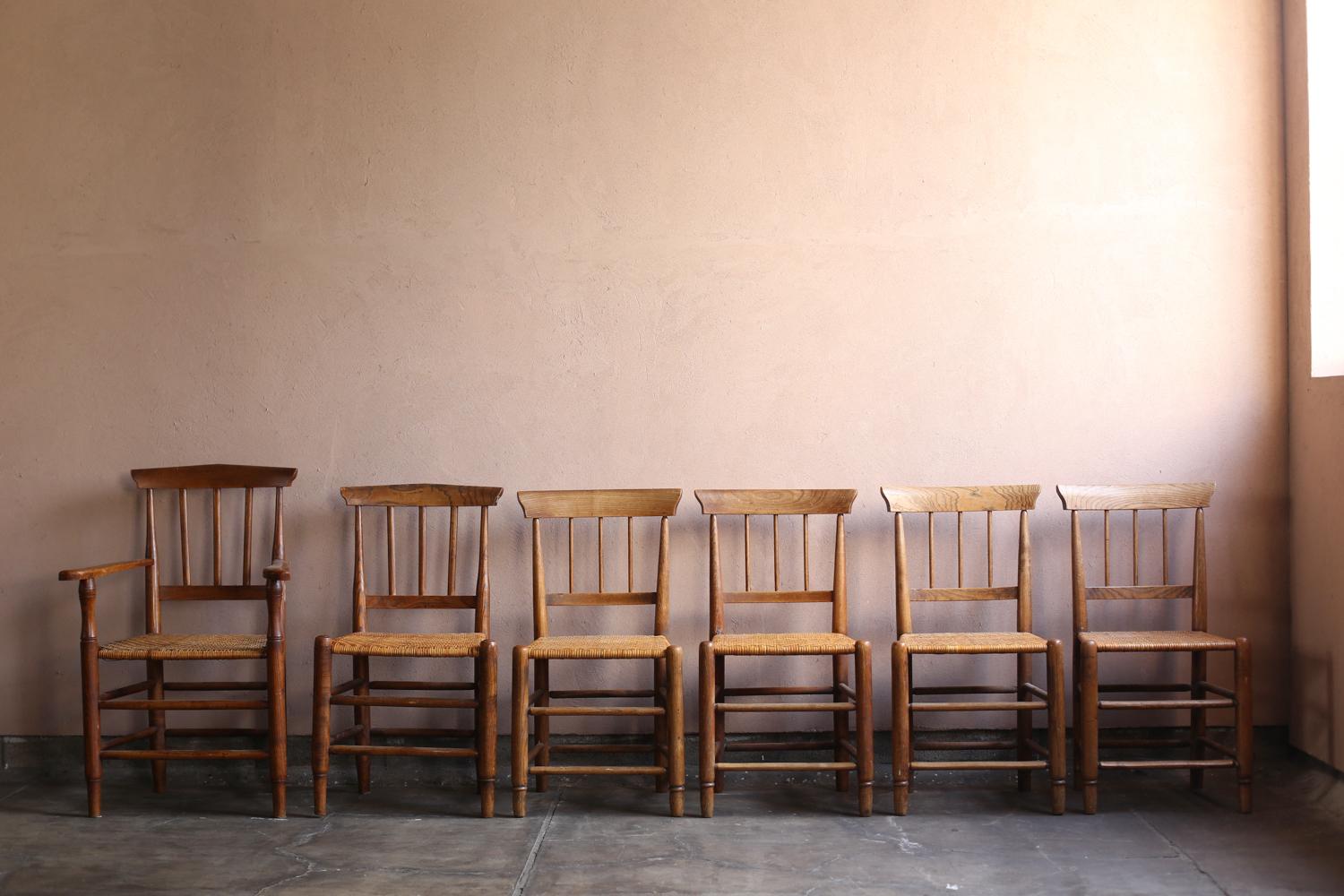 Questo set di sei sedie provinciali francesi (una delle quali è una poltrona) risale agli inizi del XX secolo. Con schienali e gambe in legno massiccio e sedute in giunco intrecciato, presentano un design rustico che affonda le sue radici nella vita