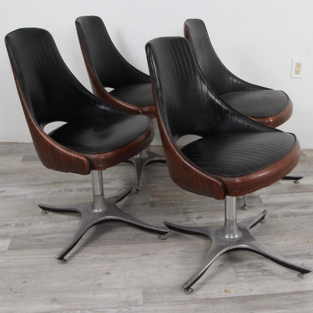 Have dealt with a few variations of Chromcraft chairs in the last few years, but never a set with these rare bases. Very Jetsons in appearance. A mix of faux wood and black naugahyde atop a brushed steel base. Chairs swivel 360 degrees.