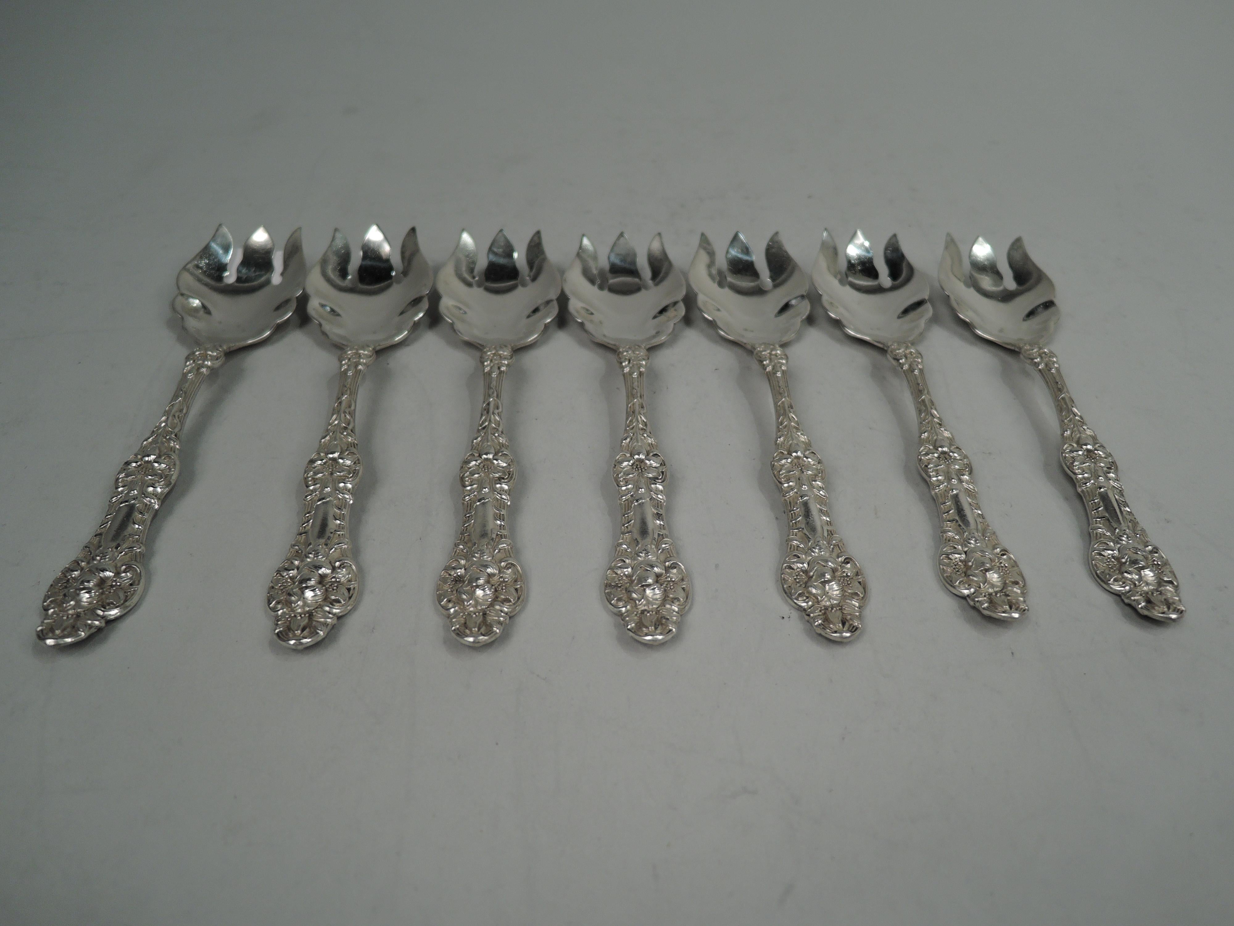 Set of 7 Orange Blossom sterling silver ice cream forks. Made by Alvin Corporation in Providence, ca 1910. Each: Deep and scrolled 3-tine shank; floral ornament on scrolled and reeded stem with trefoil terminal. Fully marked including maker’s stamp.