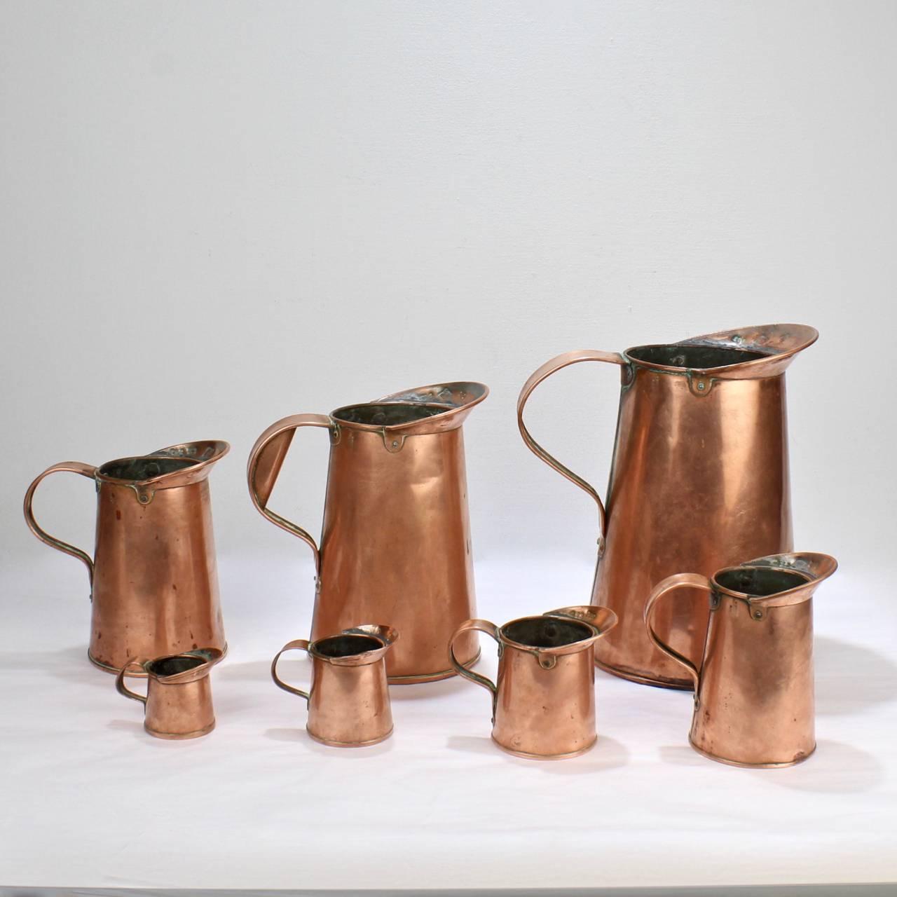 A wonderful set of 19th century New York City antique copper measures.

Comprised of seven pitcher form, tin lined measures in descending sizes. Stamped with various numbers and letters.

Marked for and sold by B. Budde of 50 Vesey St New York,