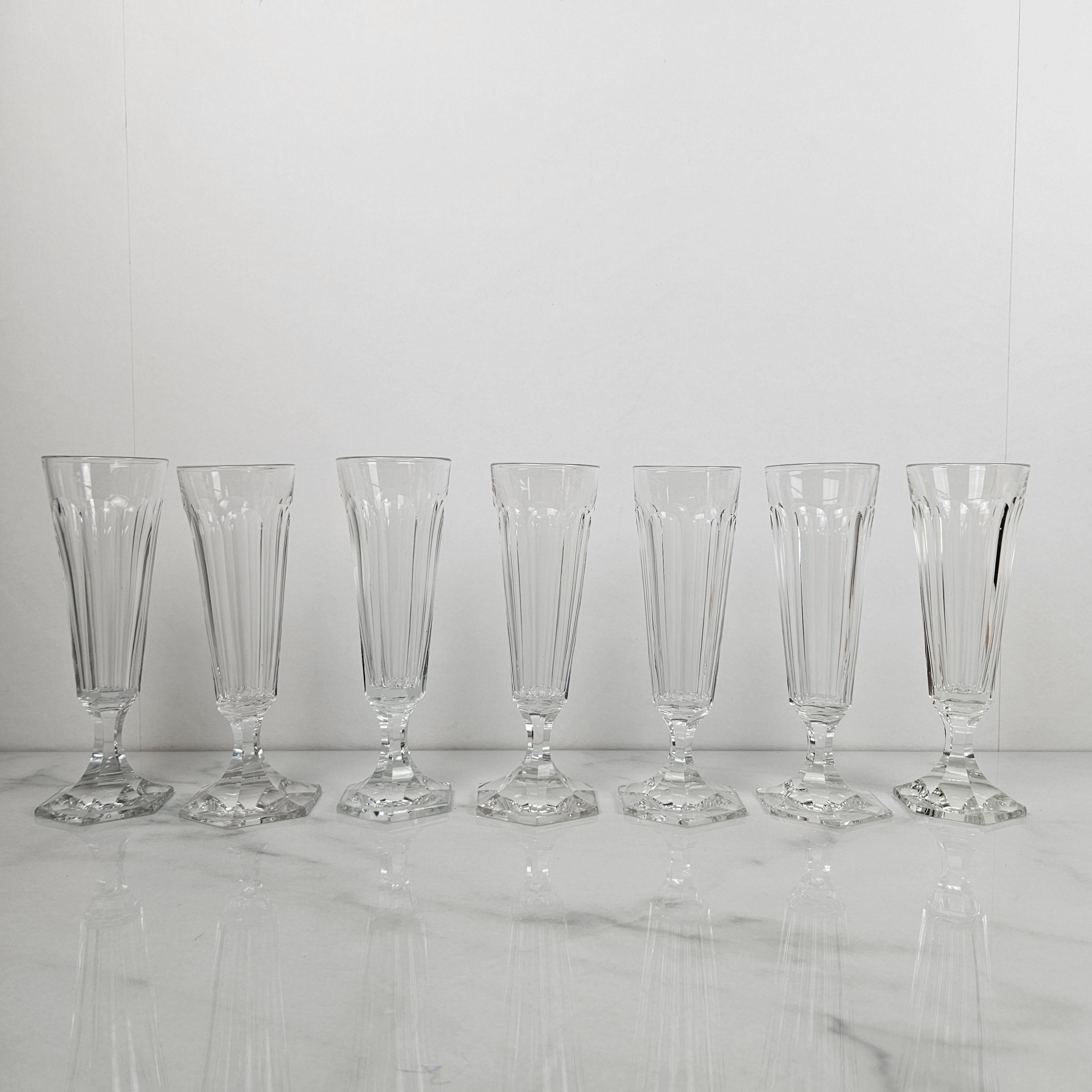 Ce remarquable ensemble de sept flûtes à champagne françaises anciennes est un bel exemple de la verrerie du XIXe siècle dans toute sa splendeur. 
Fabriquée vers 1880, chaque flûte est soufflée à la main à partir d'un cristal épais de haute qualité,
