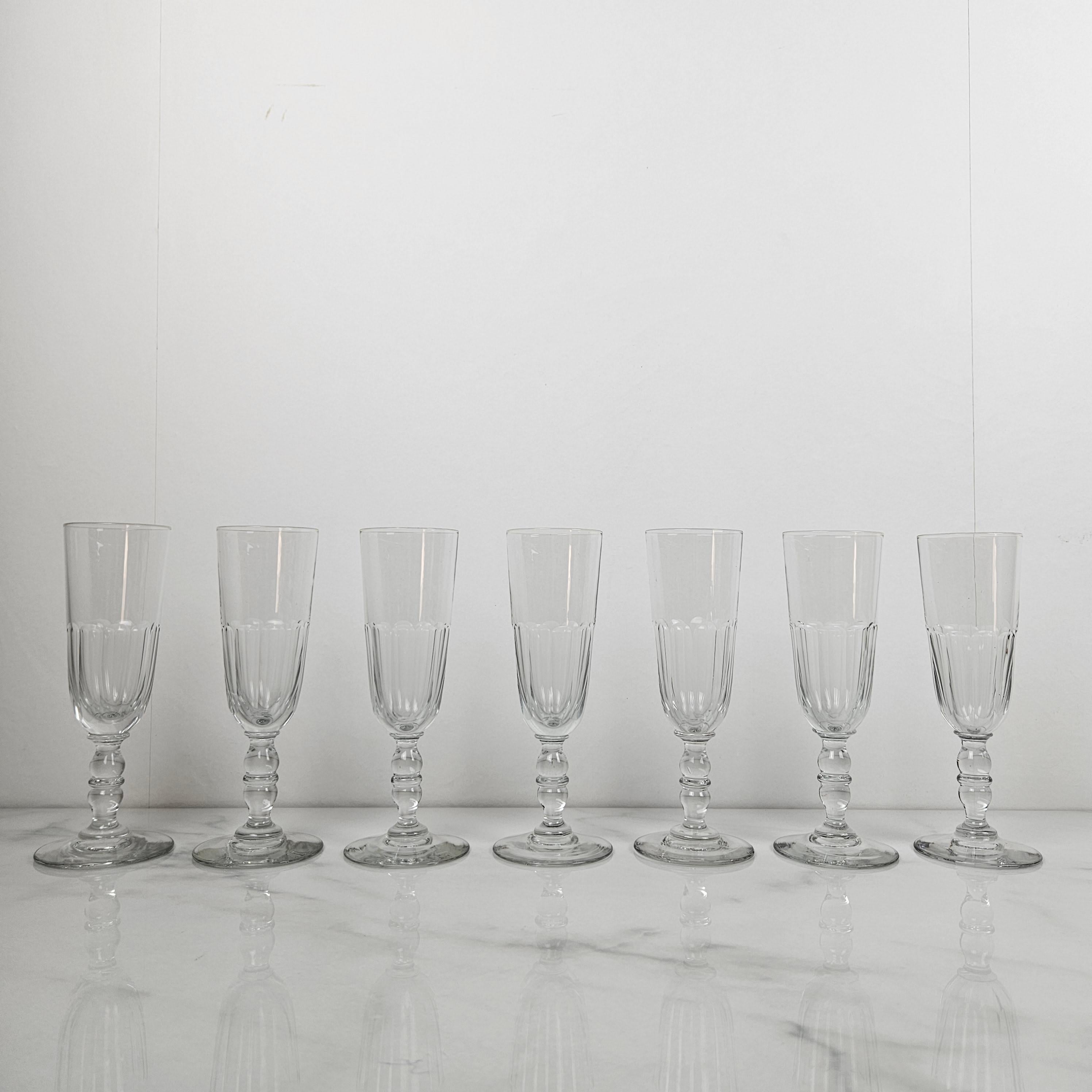 Ein seltener und eleganter Satz von sieben handgeschliffenen Champagnerflöten aus Kristall, datiert um 1880. 
Jedes Glas ist meisterhaft gefertigt, mit einer vertikal geriffelten Schale, einem wunderschön gedrehten Balusterstiel und einem polierten
