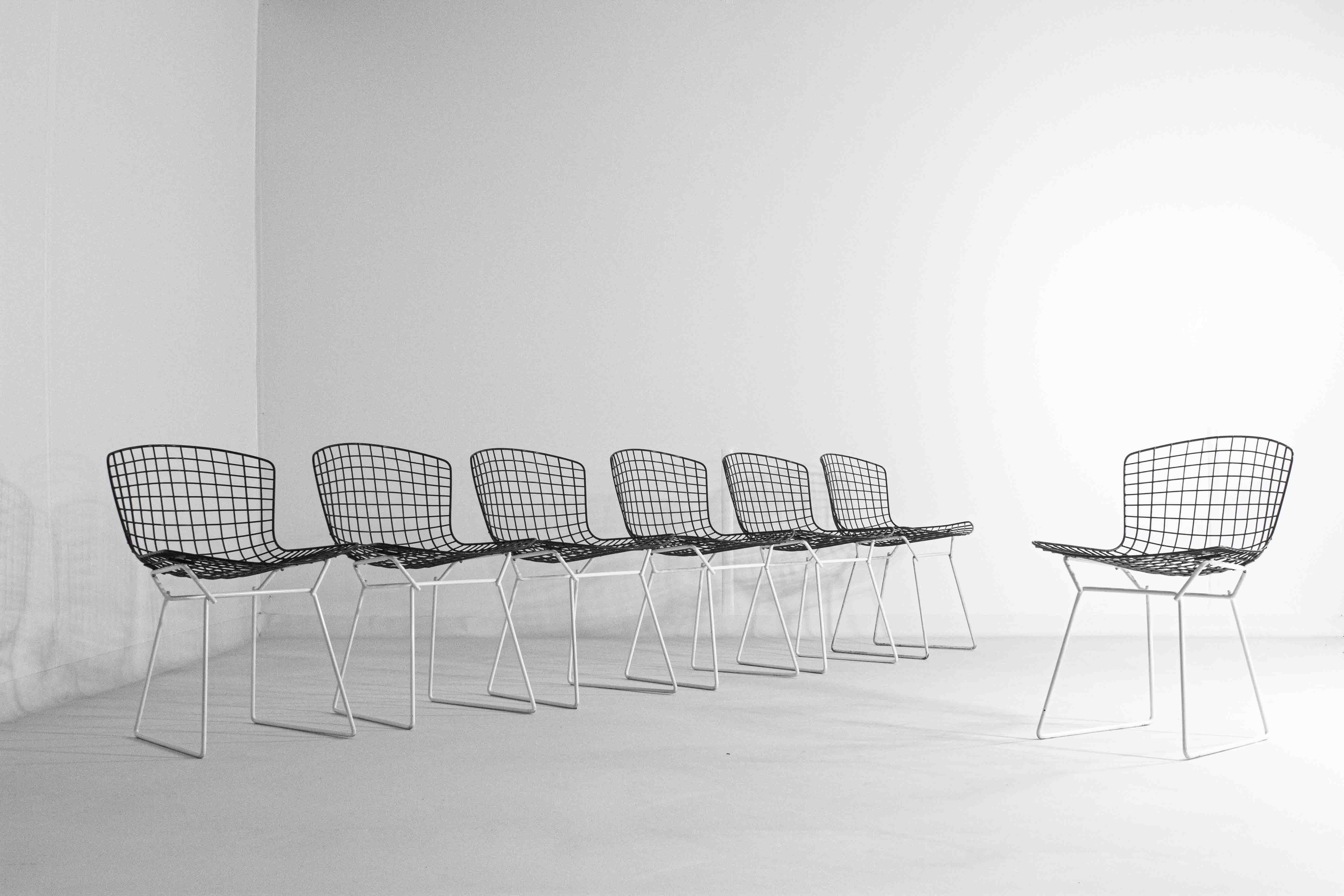 This rare configuration of the Harry Bertoia side chairs, featuring a white base paired with a black seating structure, deviates from the more common combinations typically seen in this iconic design. Produced by Knoll, this chair highlights