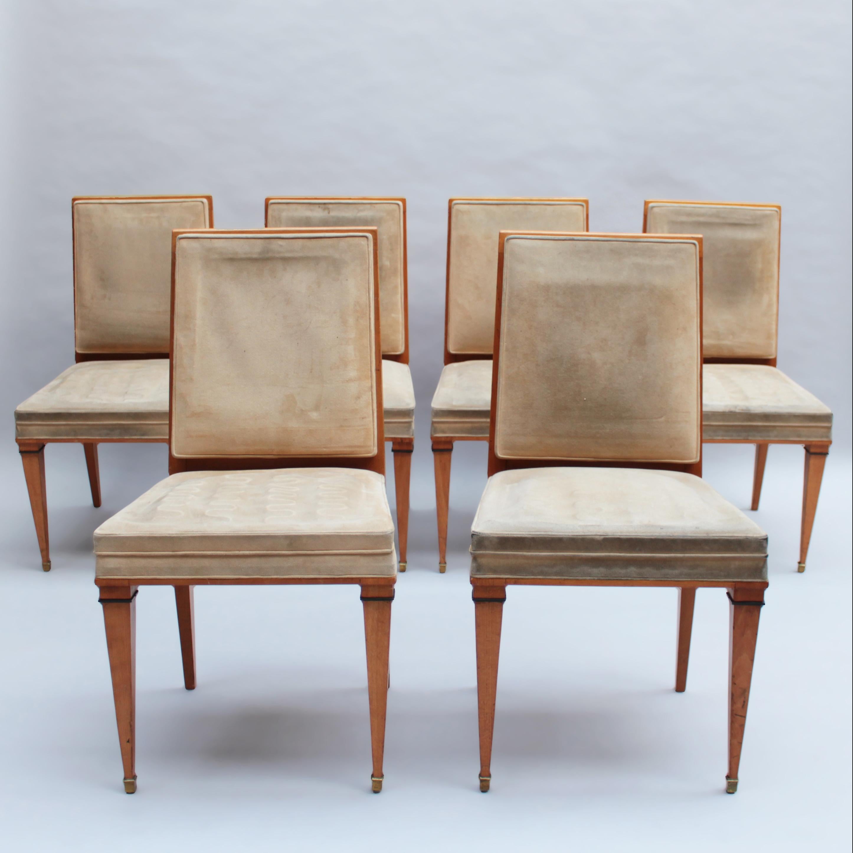 Un set di sette raffinate sedie da pranzo/accomodanti in faggio francese degli anni '40 con gambe anteriori affusolate ornate da dettagli in bronzo.

